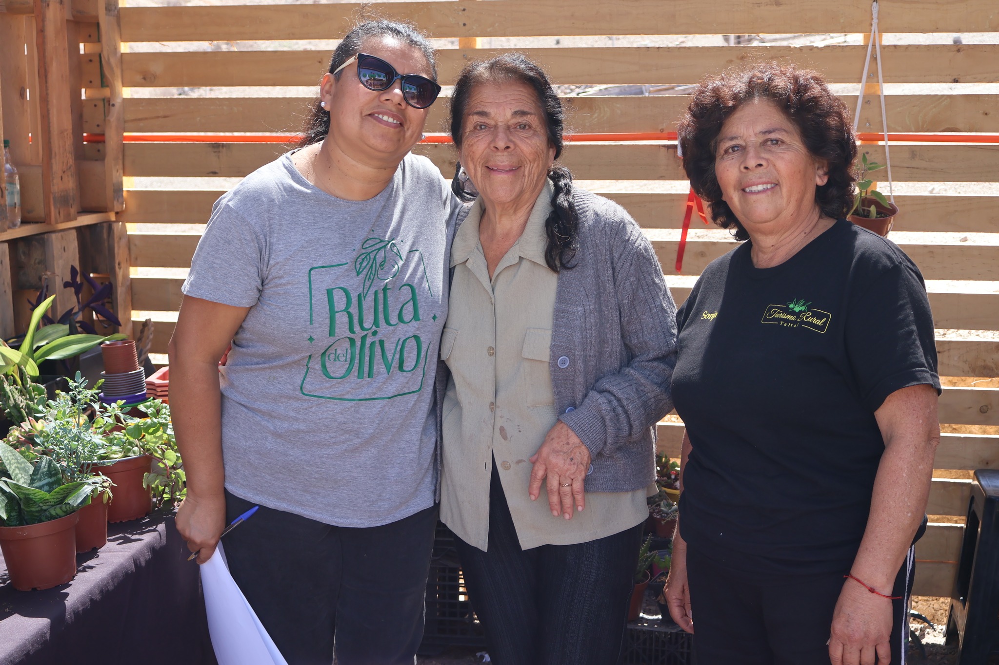 Integrantes de la Comunidad Agrícola Los Loros posan en su stand de plantas y productos naturales.