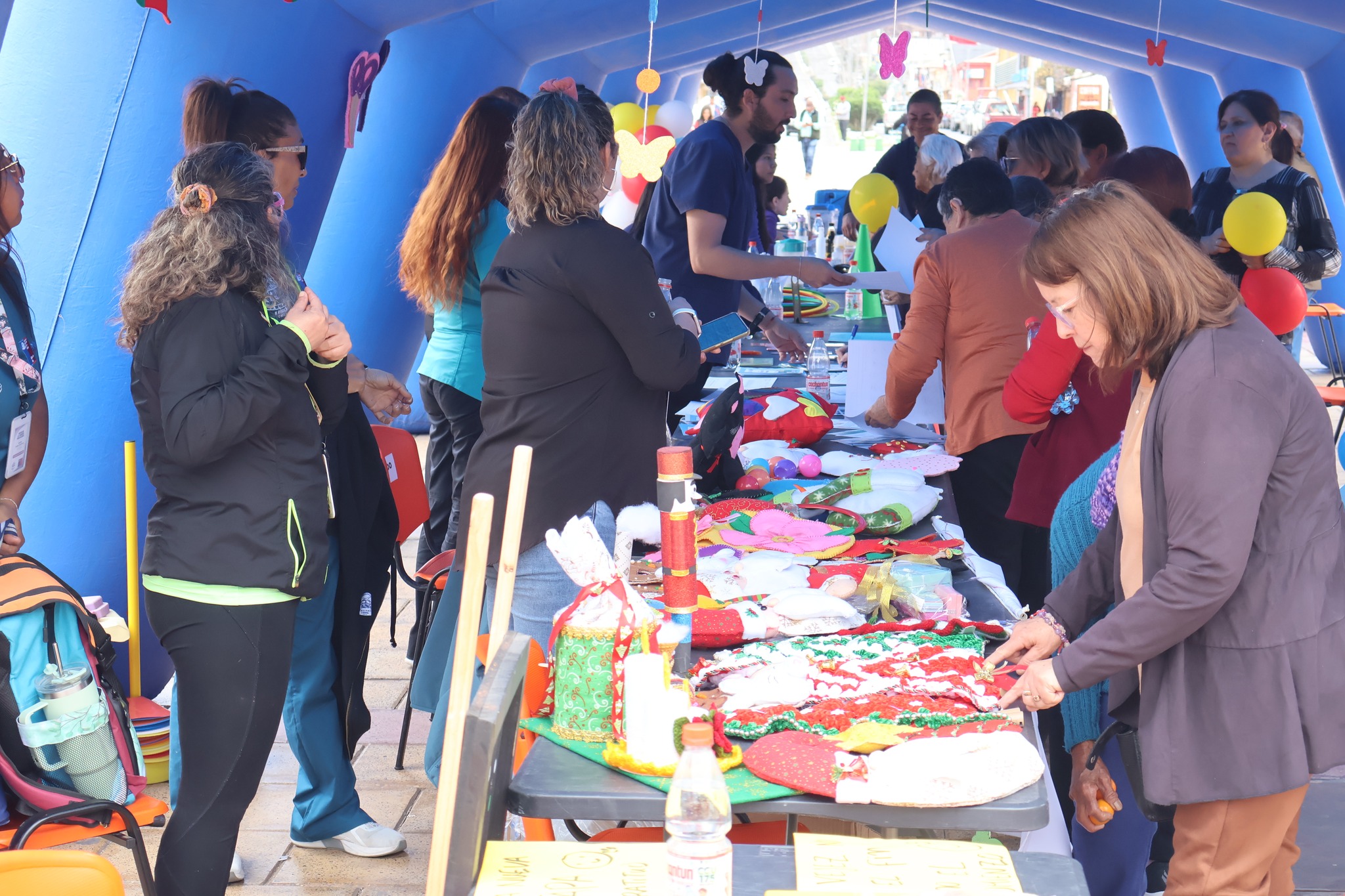 Puesto de feria o bazar de artesanías hechas por la comunidad bajo una carpa azul.