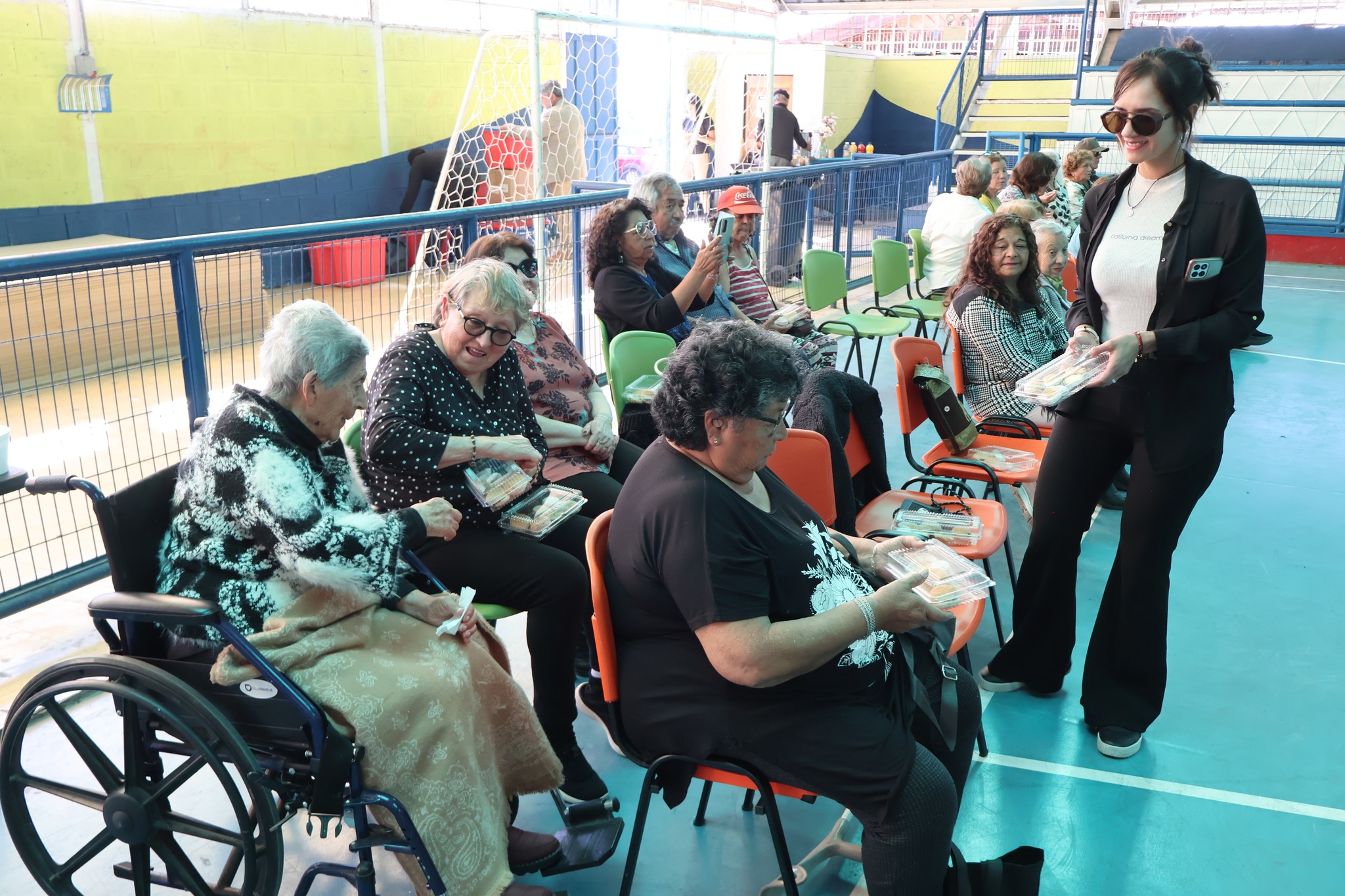 Adultos mayores disfrutan de un momento de camaradería junto al equipo municipal que entrega colaciones.