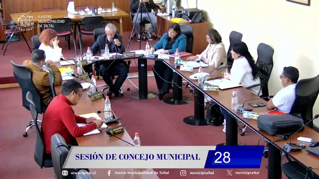 Concejales de Taltal en sesión ordinaria; dos ediles conversan frente a micrófonos en sala municipal de madera