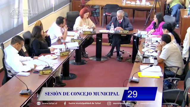 Concejales de Taltal en sesión ordinaria; dos ediles conversan frente a micrófonos en sala municipal de madera