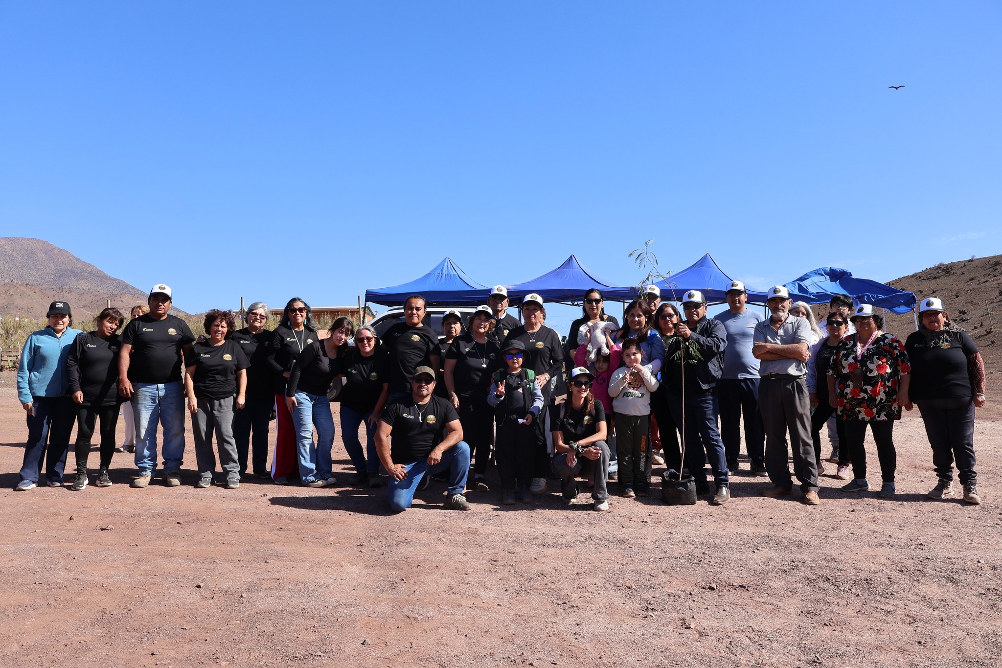 Equipo organizador y comunidad agrícola de El Hueso posan en grupo durante la feria costumbrista AgroTaltal 2025, bajo un cielo despejado y entorno rural.