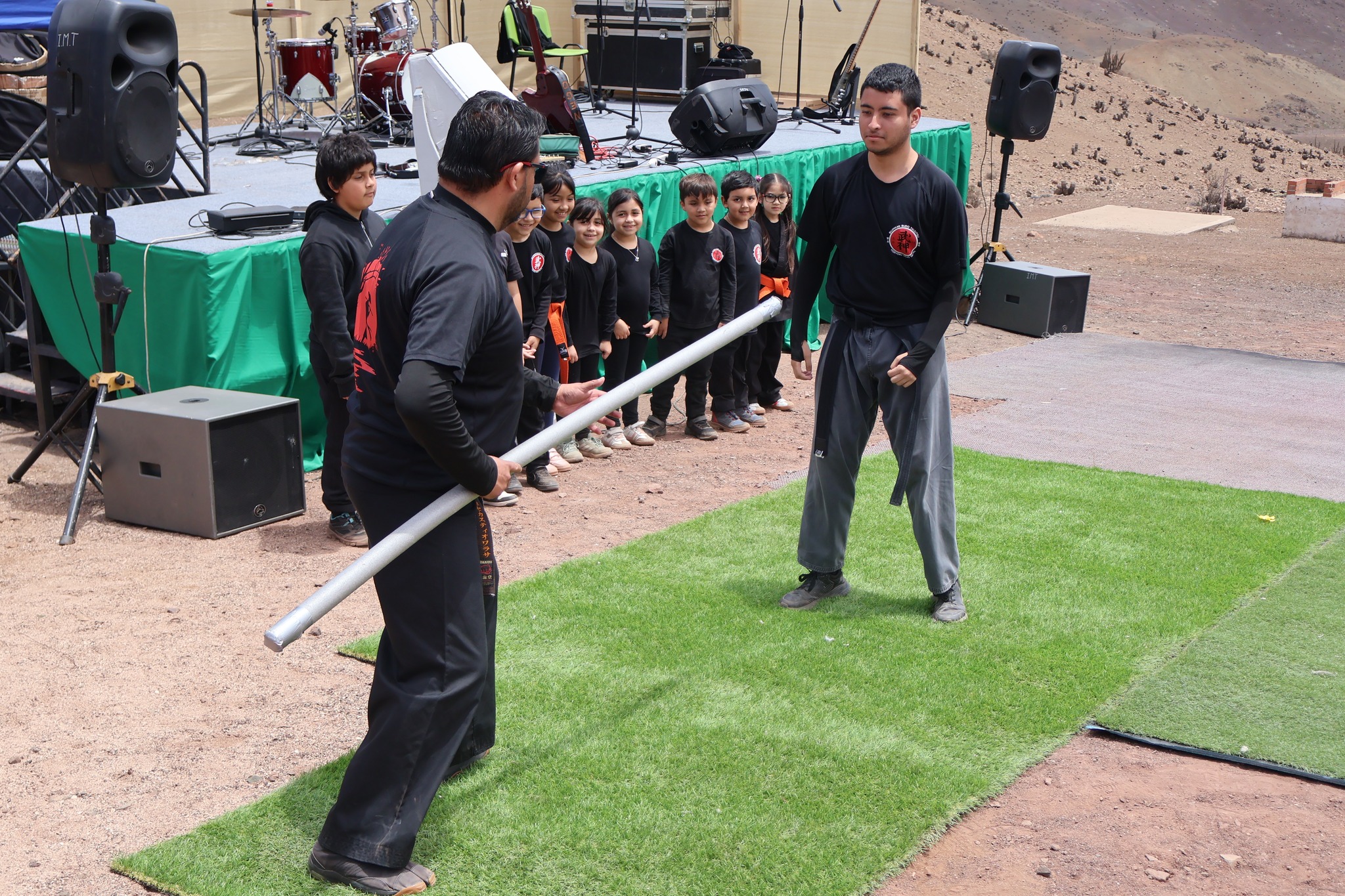 Instructor y alumno del taller municipal de artes marciales realizan demostración con bastón durante AgroTaltal 2025 en El Hueso.