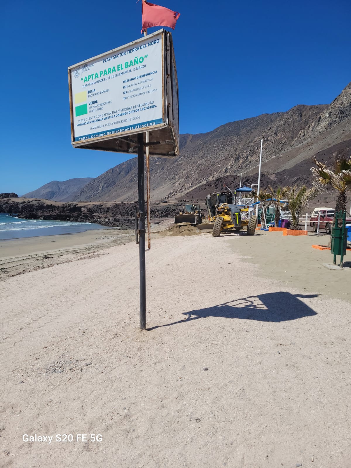 Cartel informativo “Apta para el baño” en Playa Tierra del Moro, con maquinaria municipal trabajando en el borde costero de Taltal.