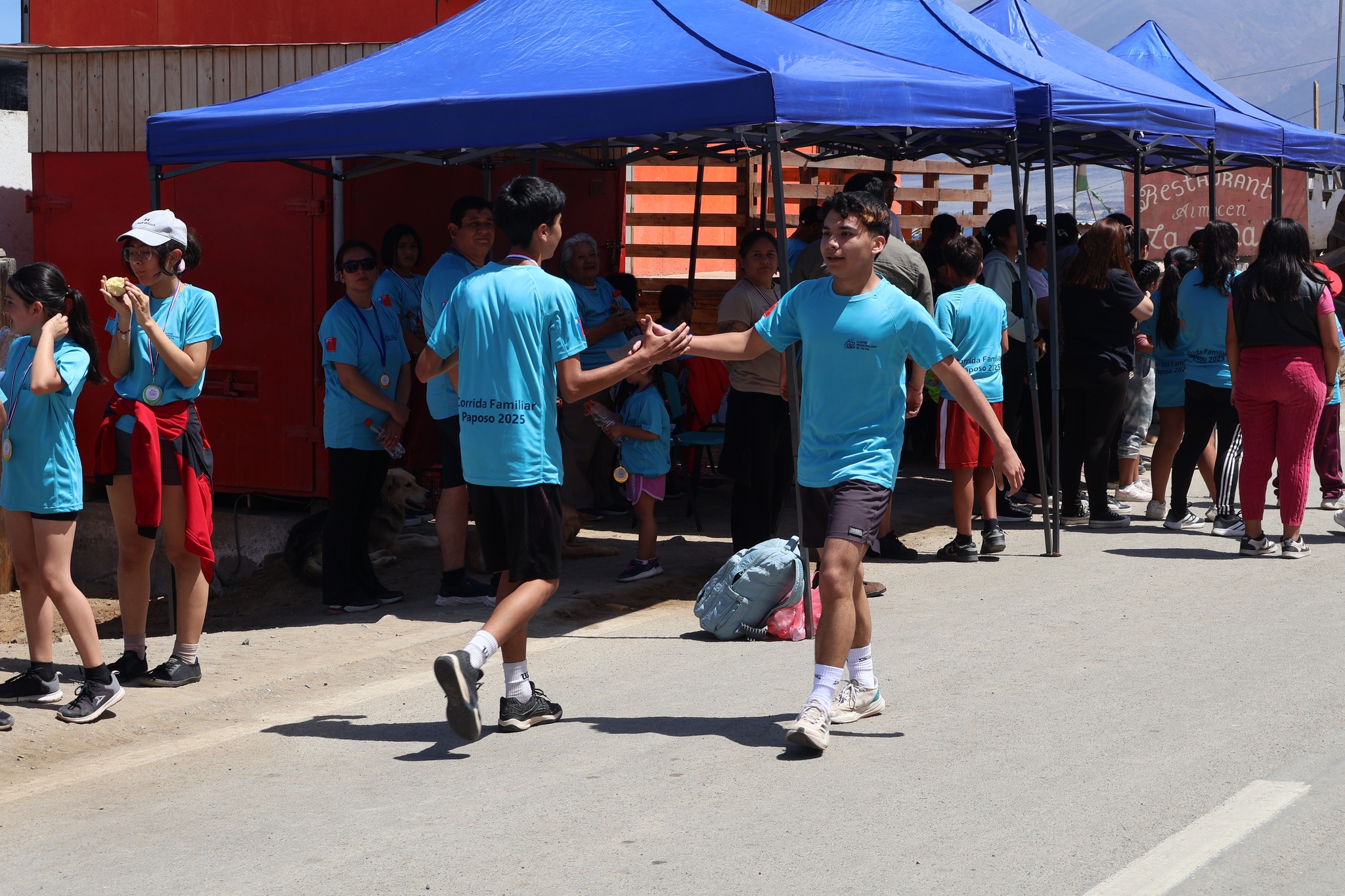 Corredores se felicitan tras completar la Corrida Familiar de Paposo 2025, reflejando espíritu deportivo y camaradería.