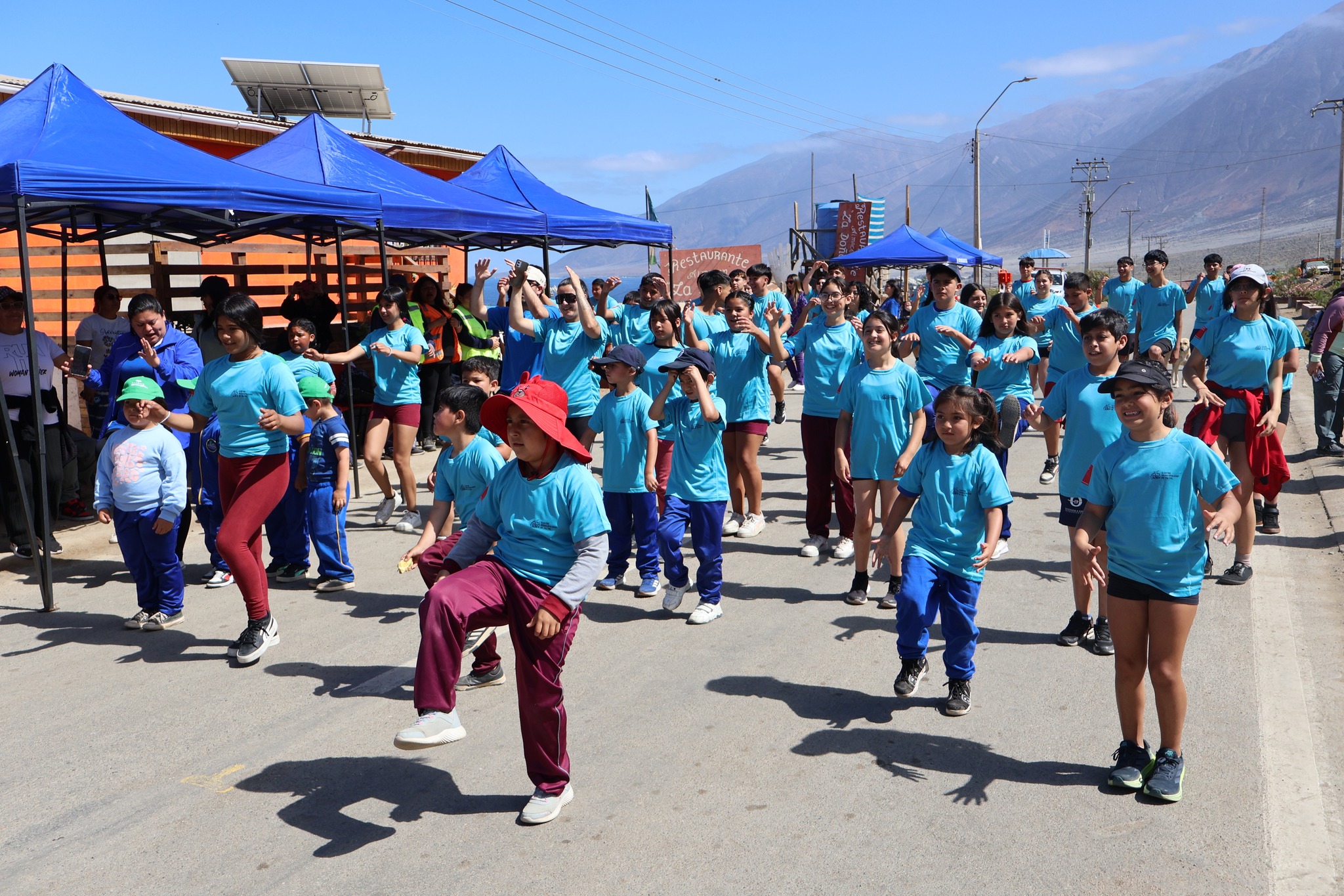 Niños y niñas realizan ejercicios dirigidos por monitores en la Corrida Familiar de Paposo 2025, promoviendo el deporte y la salud infantil.