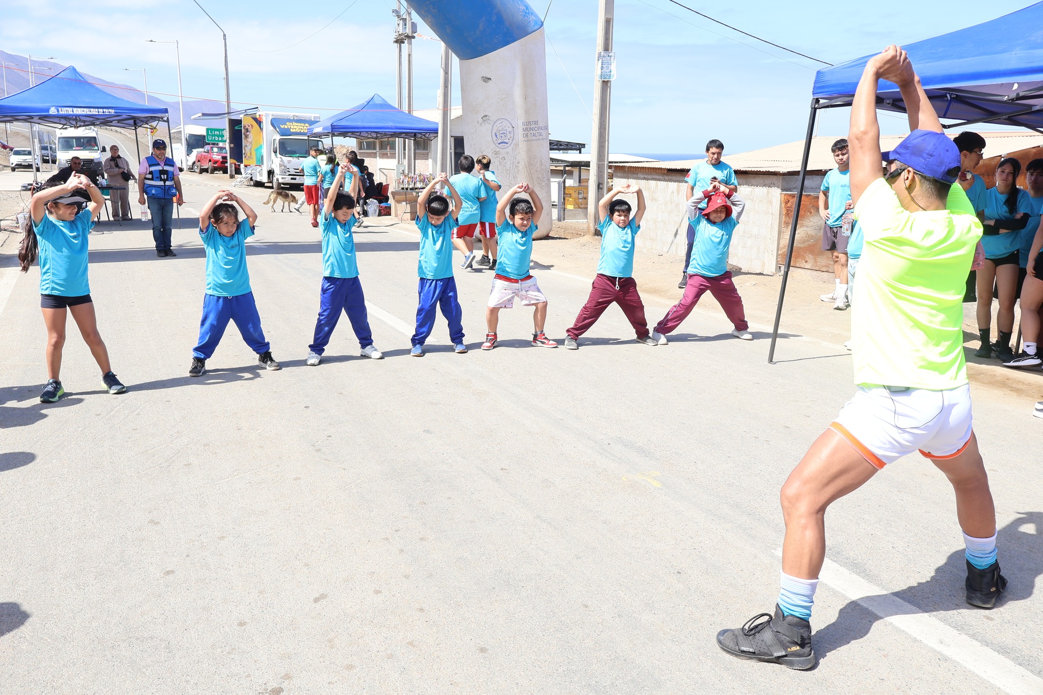 Niños y niñas realizan ejercicios guiados durante la sesión de calentamiento de la Corrida Familiar de Paposo 2025.