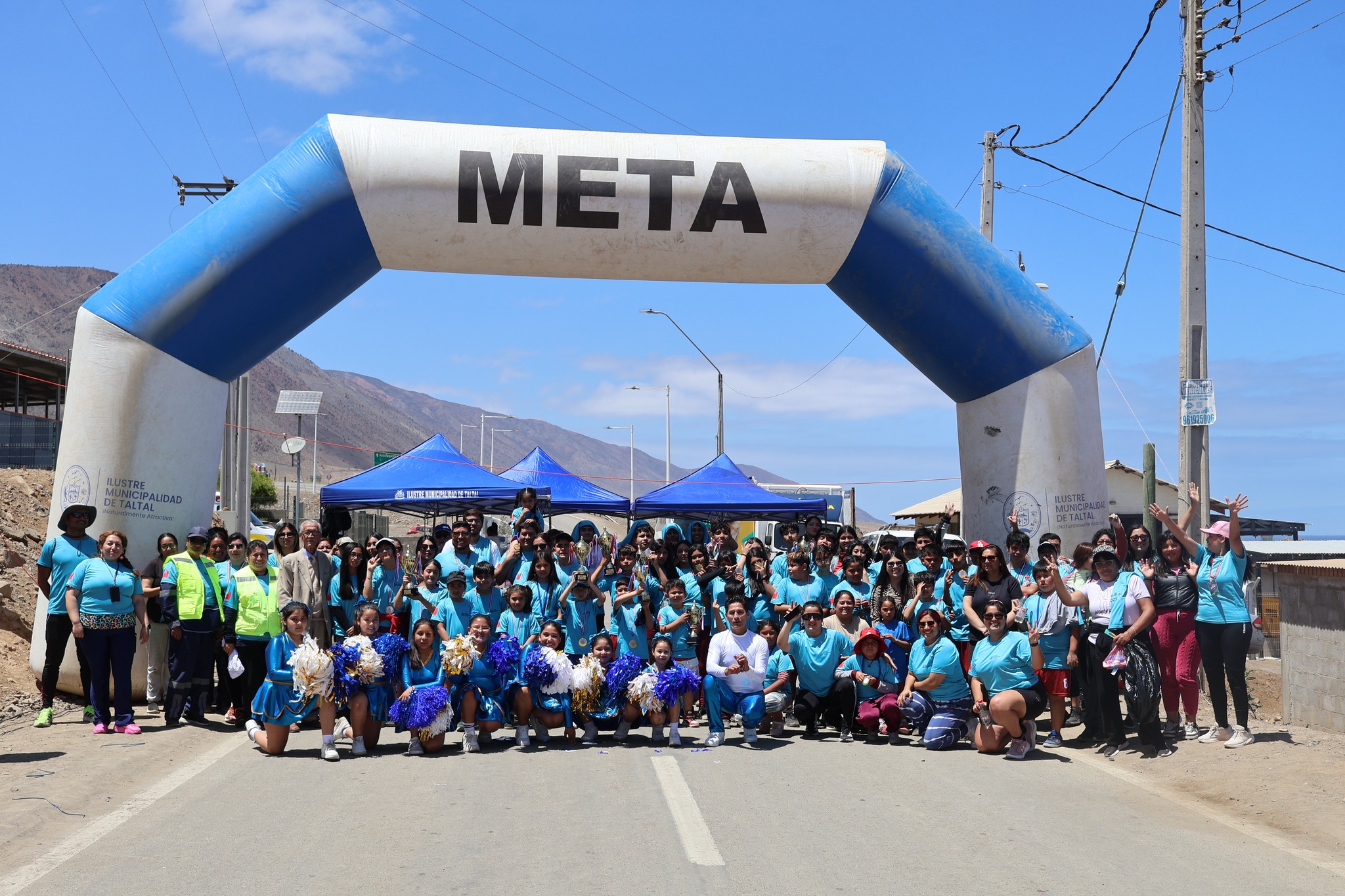 Foto grupal de participantes, organizadores y familias bajo el arco de meta de la primera Corrida Familiar de Paposo 2025.