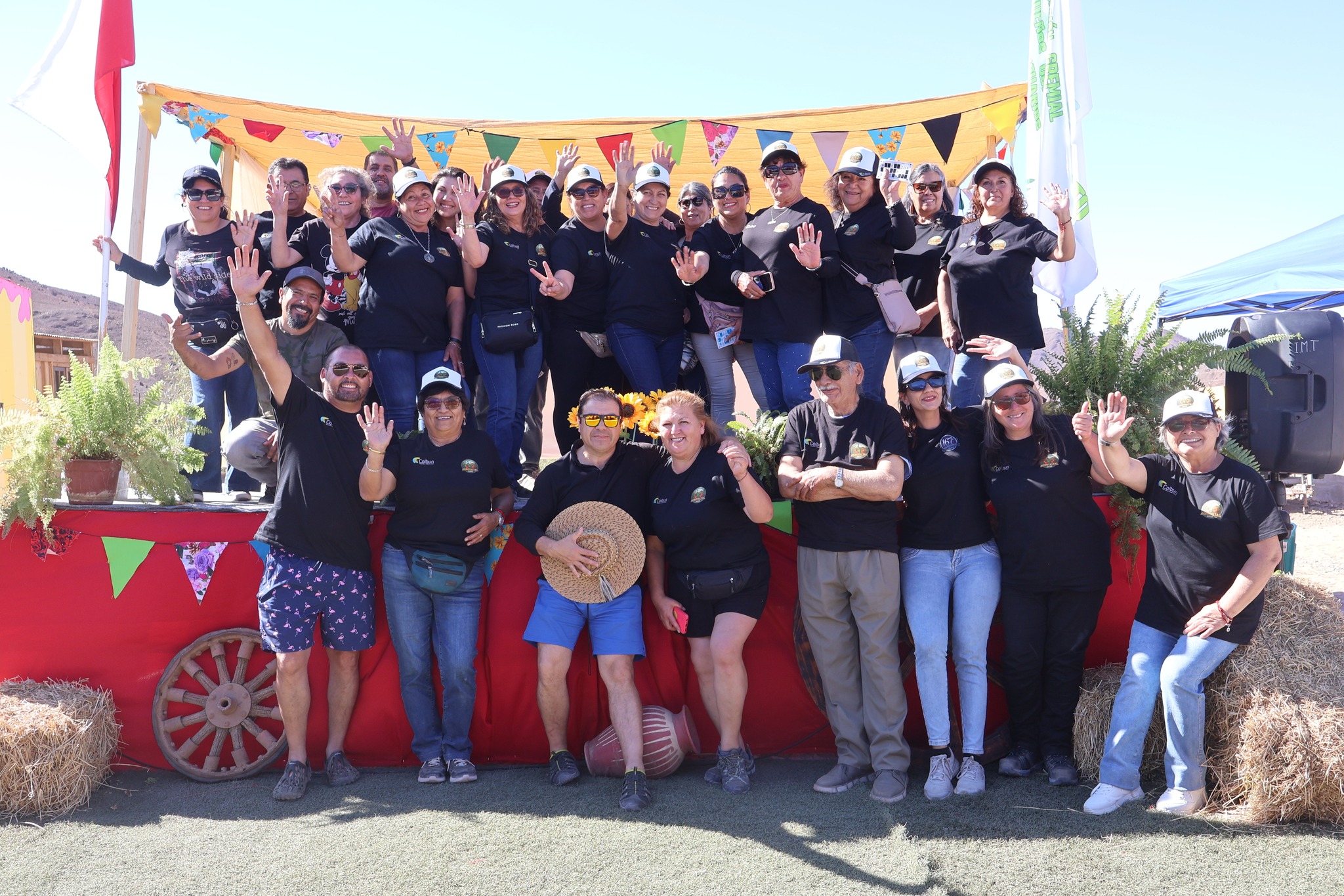 Equipo organizador y comunidad agrícola de El Hueso posan en grupo durante la feria costumbrista AgroTaltal 2025, bajo un cielo despejado y entorno rural.