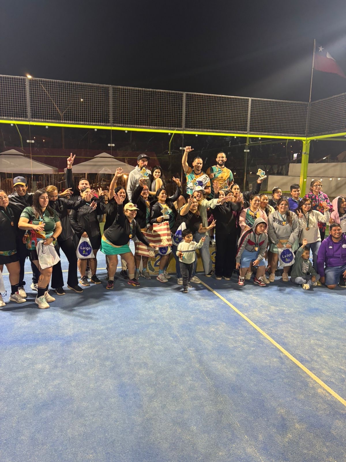 Grupo completo de jugadores, jugadoras y familias celebrando el cierre de La Liga Caleta Hueso Pádel 2025 en la cancha principal.