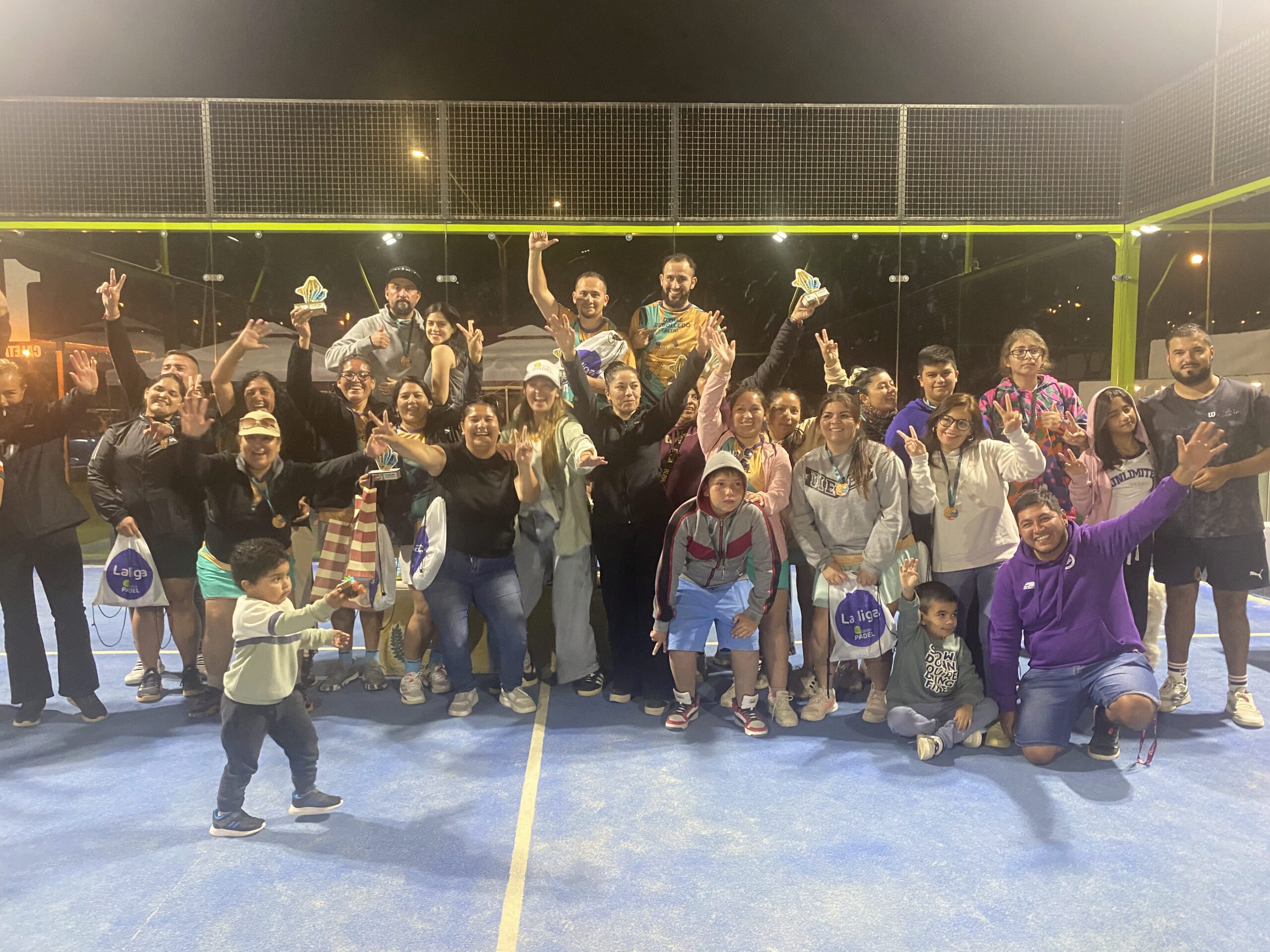 Fotografía grupal de jugadoras, jugadores, familias y organización celebrando la premiación final de La Liga Caleta Hueso Pádel 2025 en Taltal, tomada sobre la cancha tras una jornada completa de competencia.