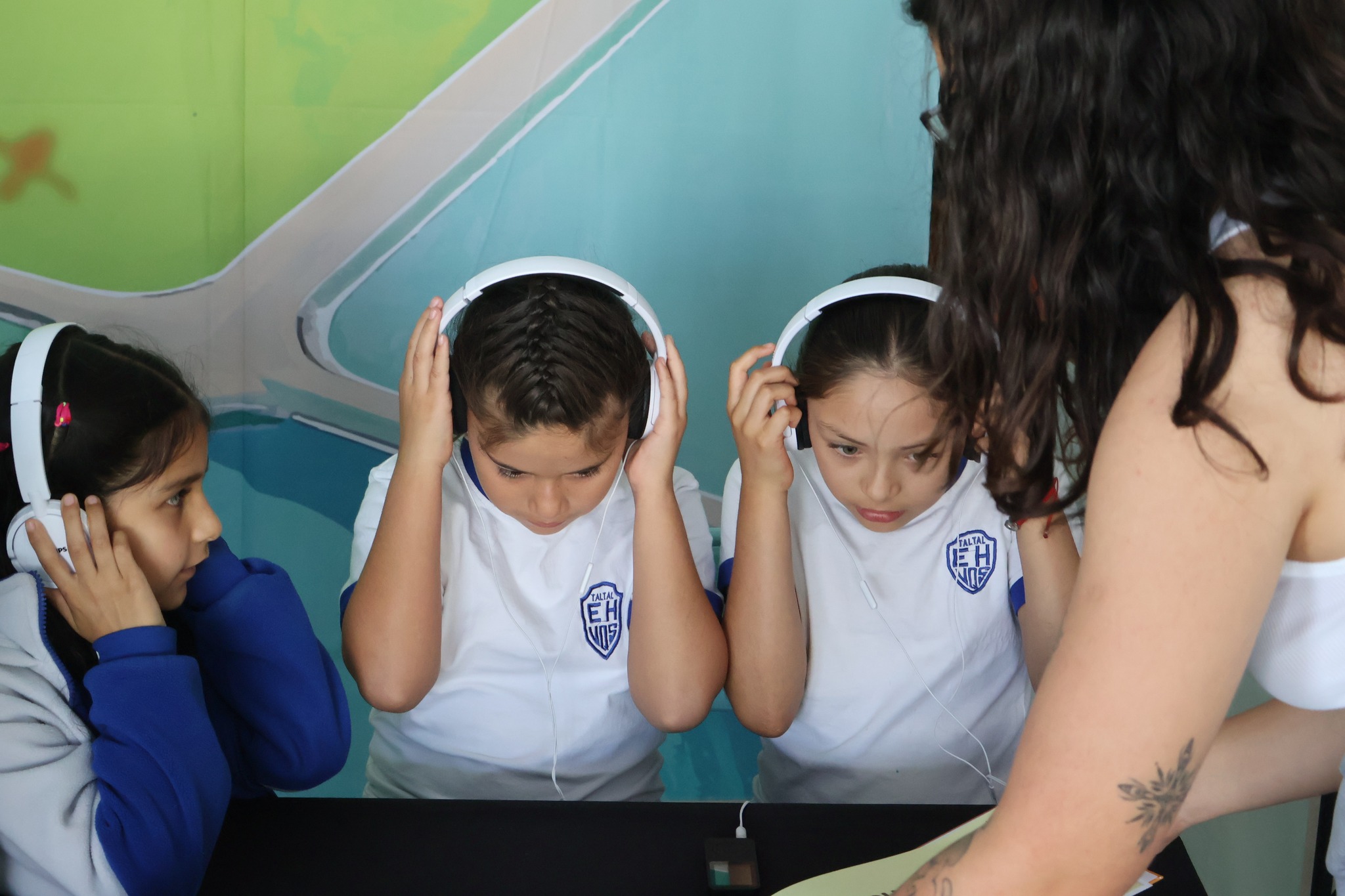 Primer plano de estudiantes concentrados escuchando el audiolibro del cuento Tataira sobre el litio.