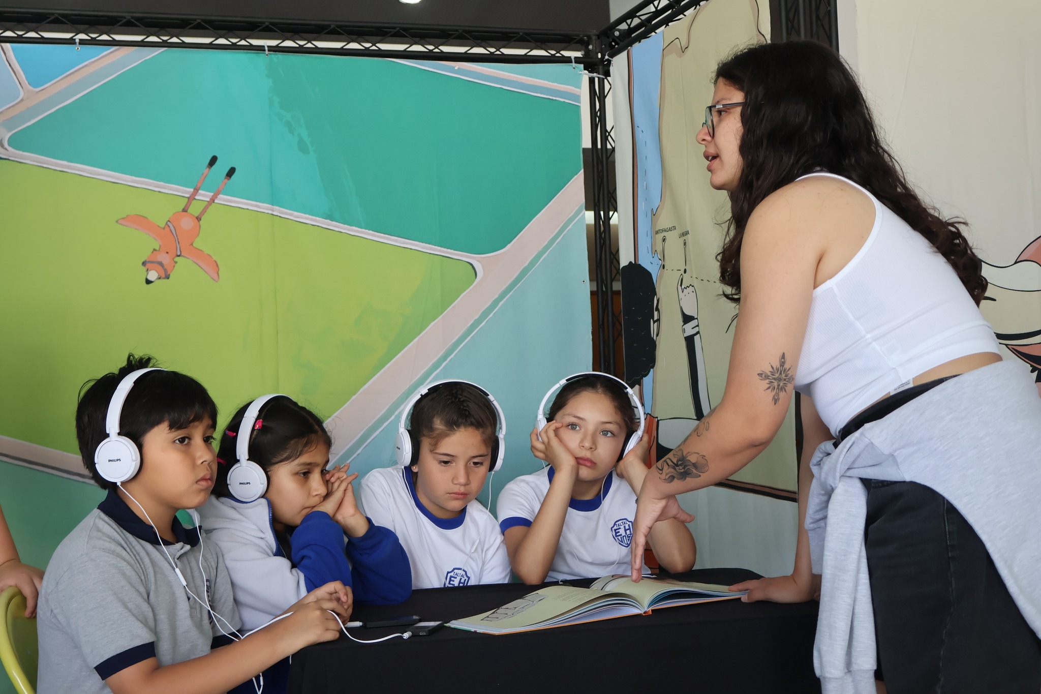 Grupo de niñas y niños escuchando el audiolibro del proyecto Tataira mientras una facilitadora guía la lectura.