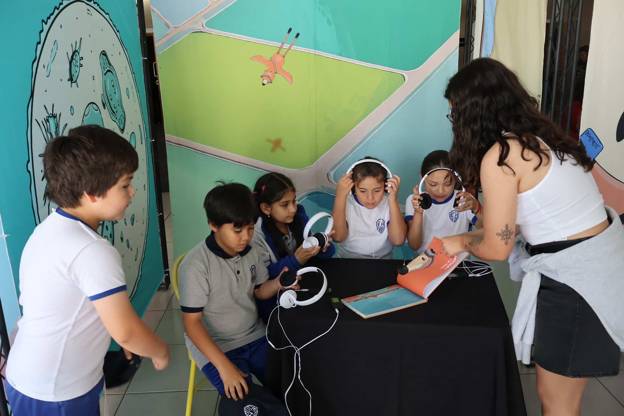 Estudiantes utilizando audífonos para escuchar el audiolibro interactivo del proyecto Tataira.