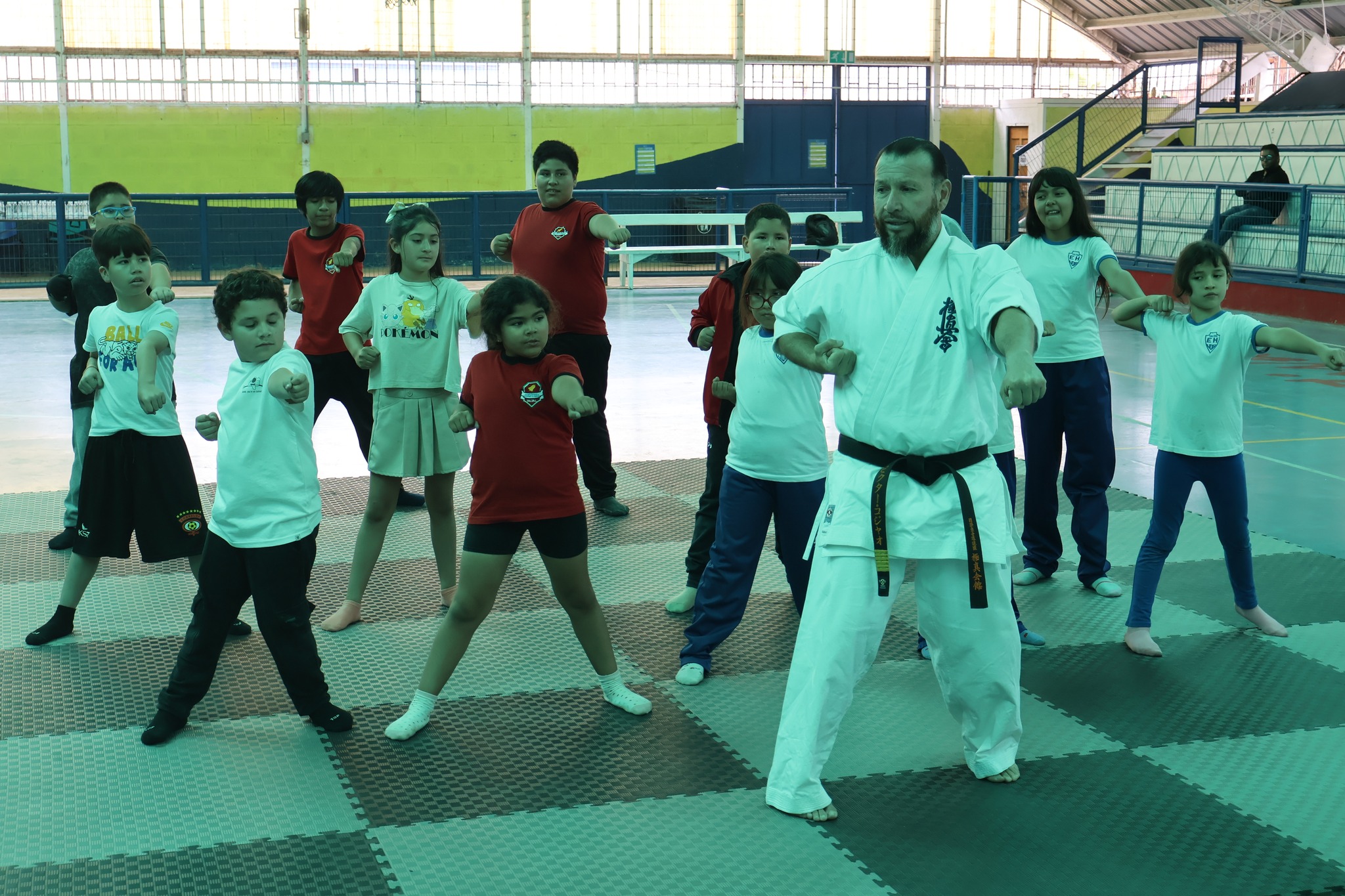 Grupo de niños y niñas del Polideportivo de Taltal practica posiciones básicas de karate guiados por el sensei Víctor Collao durante la clase abierta.