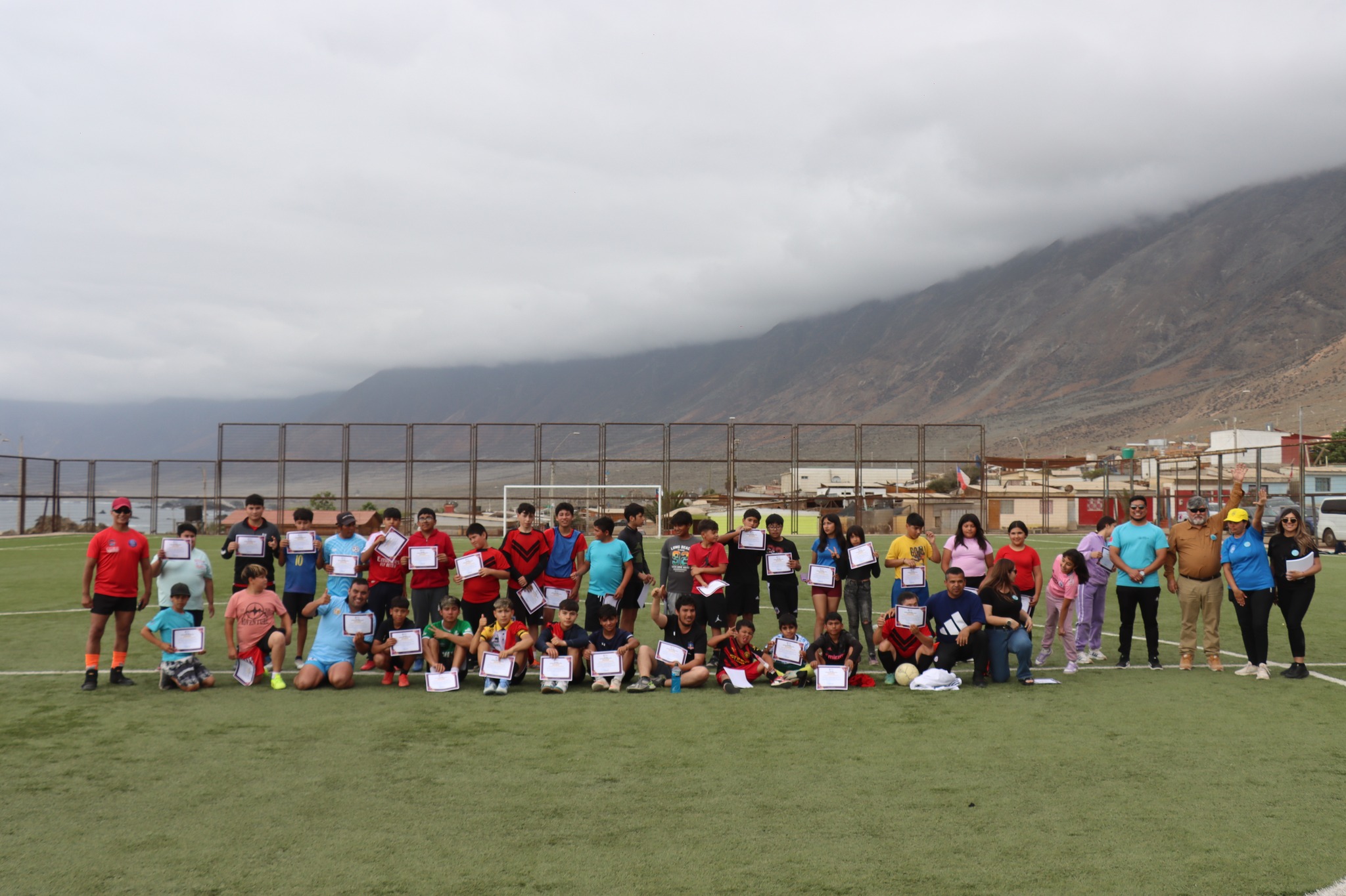 Foto grupal con niños, jóvenes y adultos mostrando diplomas del cierre del programa.
