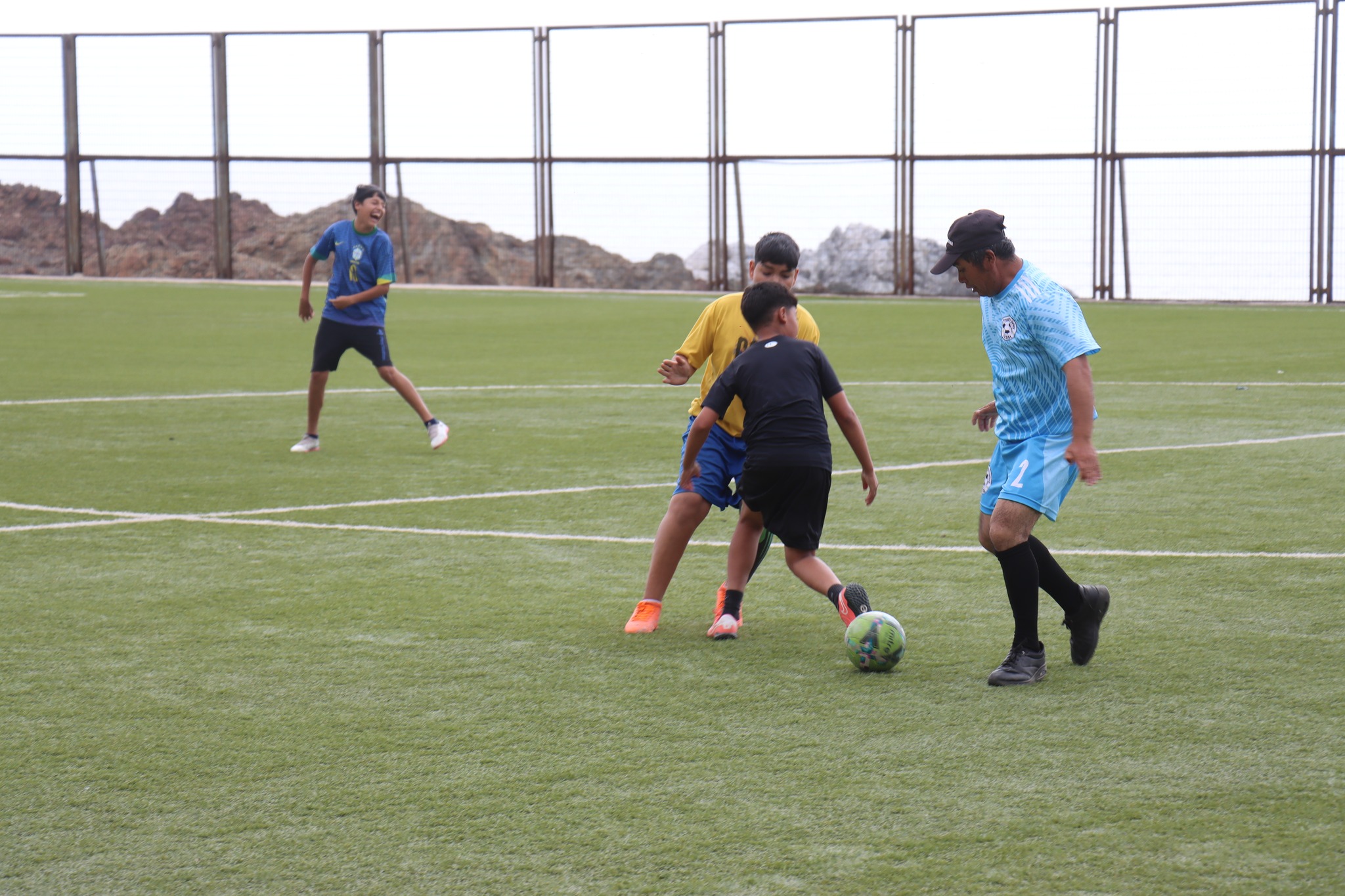 Partido de fútbol recreativo entre jóvenes y adultos en cancha de Paposo.