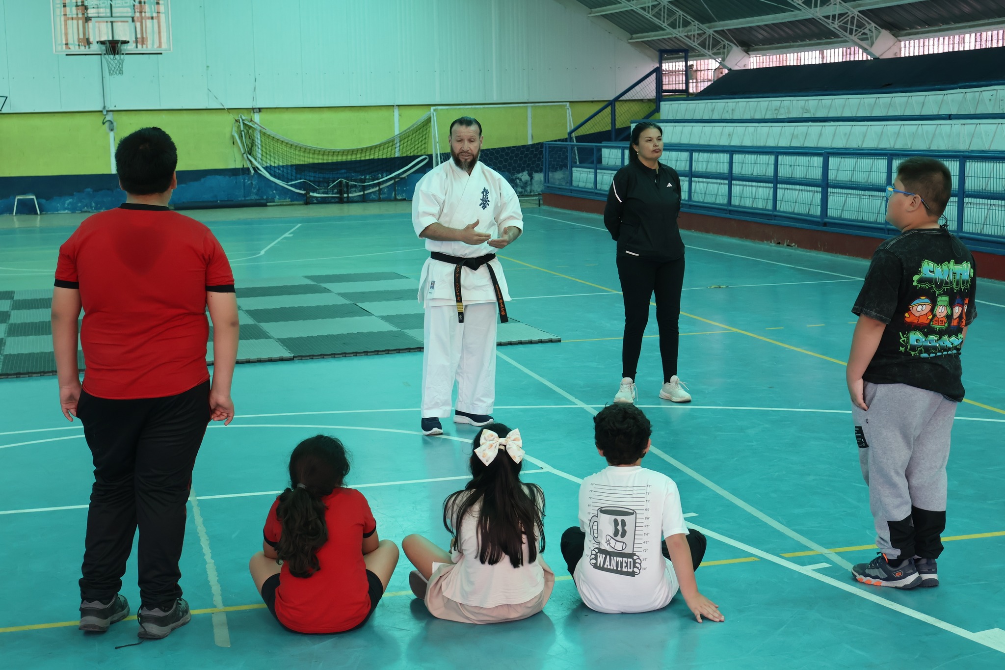 Estudiantes realizan el saludo tradicional de inicio sobre el tatami mientras los instructores observan y guían la práctica.