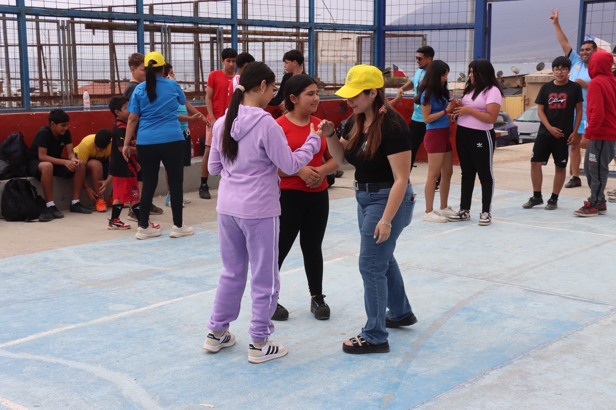 Jóvenes y niñas participando en dinámica recreativa en multicancha.