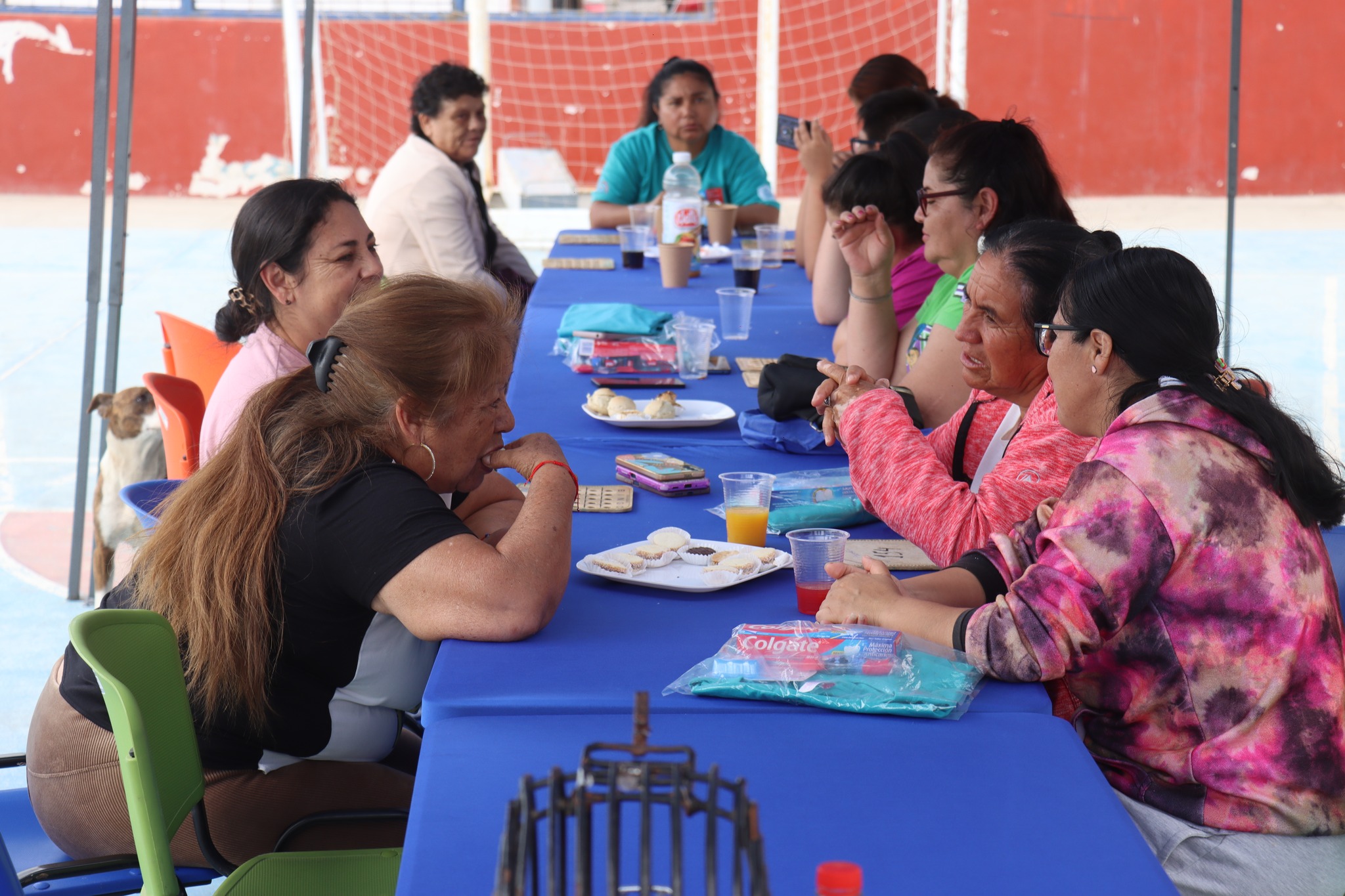 Vecinas compartiendo comida y conversación durante bingo social comunitario.