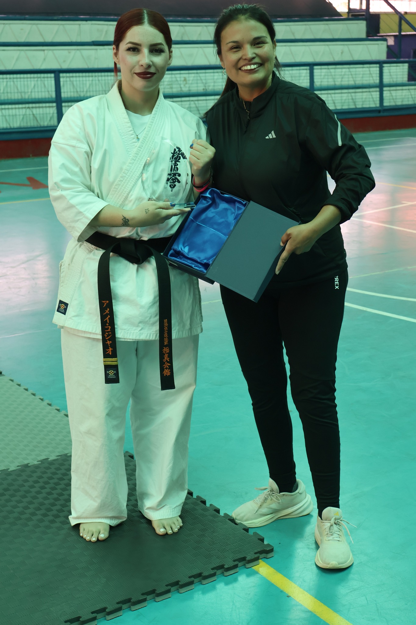 La karateka Amei Collao, vicecampeona mundial, recibe un galardón de manos de la encargada de Deportes y Cultura, Caren Huentupil, durante la actividad formativa en Taltal.