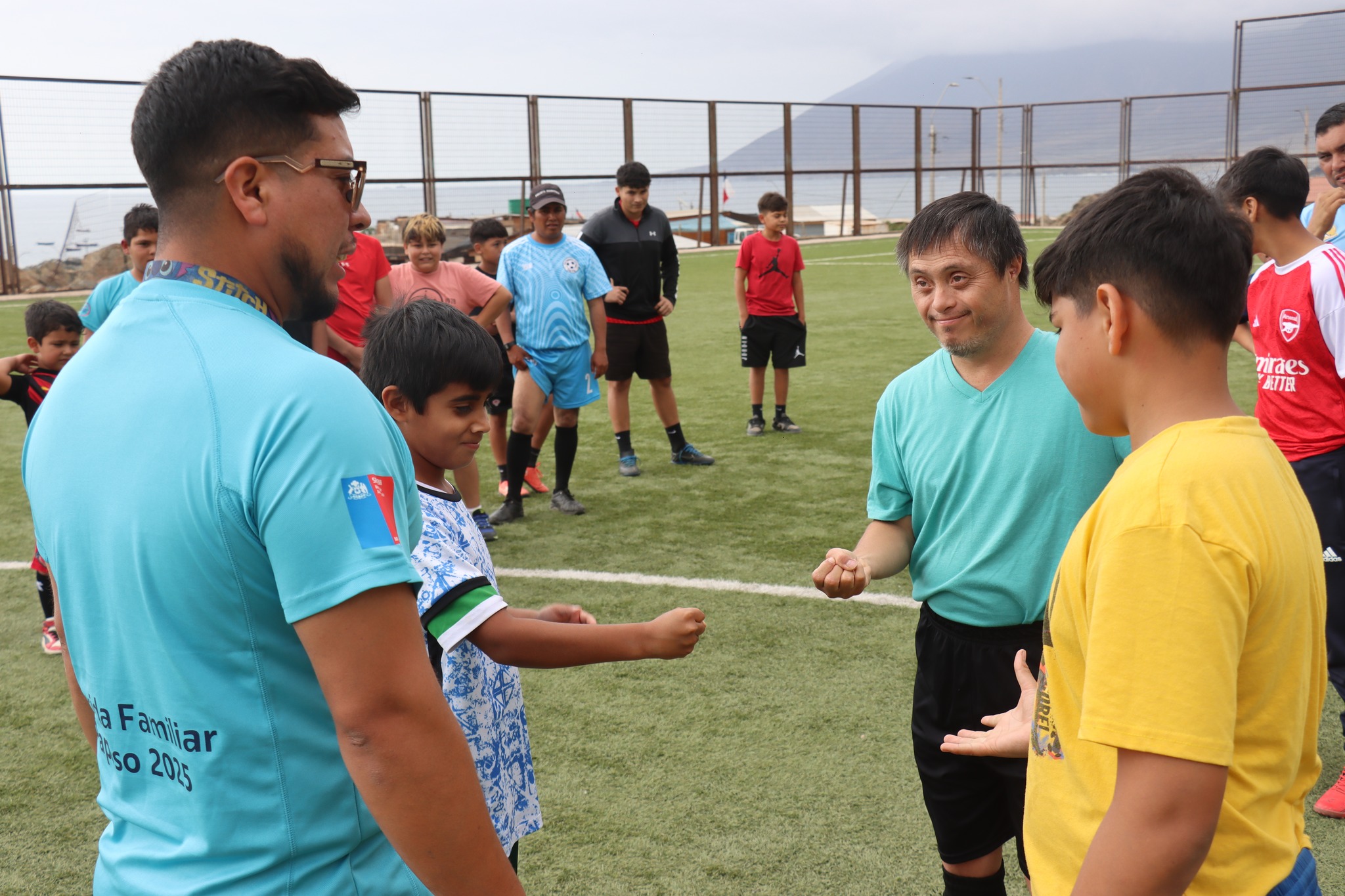 Dinámica inicial de fútbol con niños y monitor en actividad deportiva inclusiva.