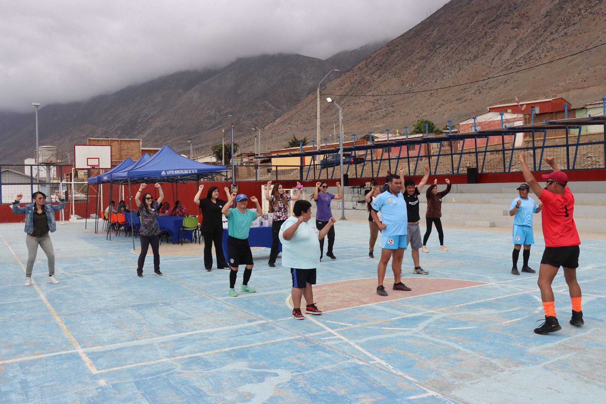 Grupo de vecinos realizando baile entretenido guiado por monitor en la cancha de Paposo.