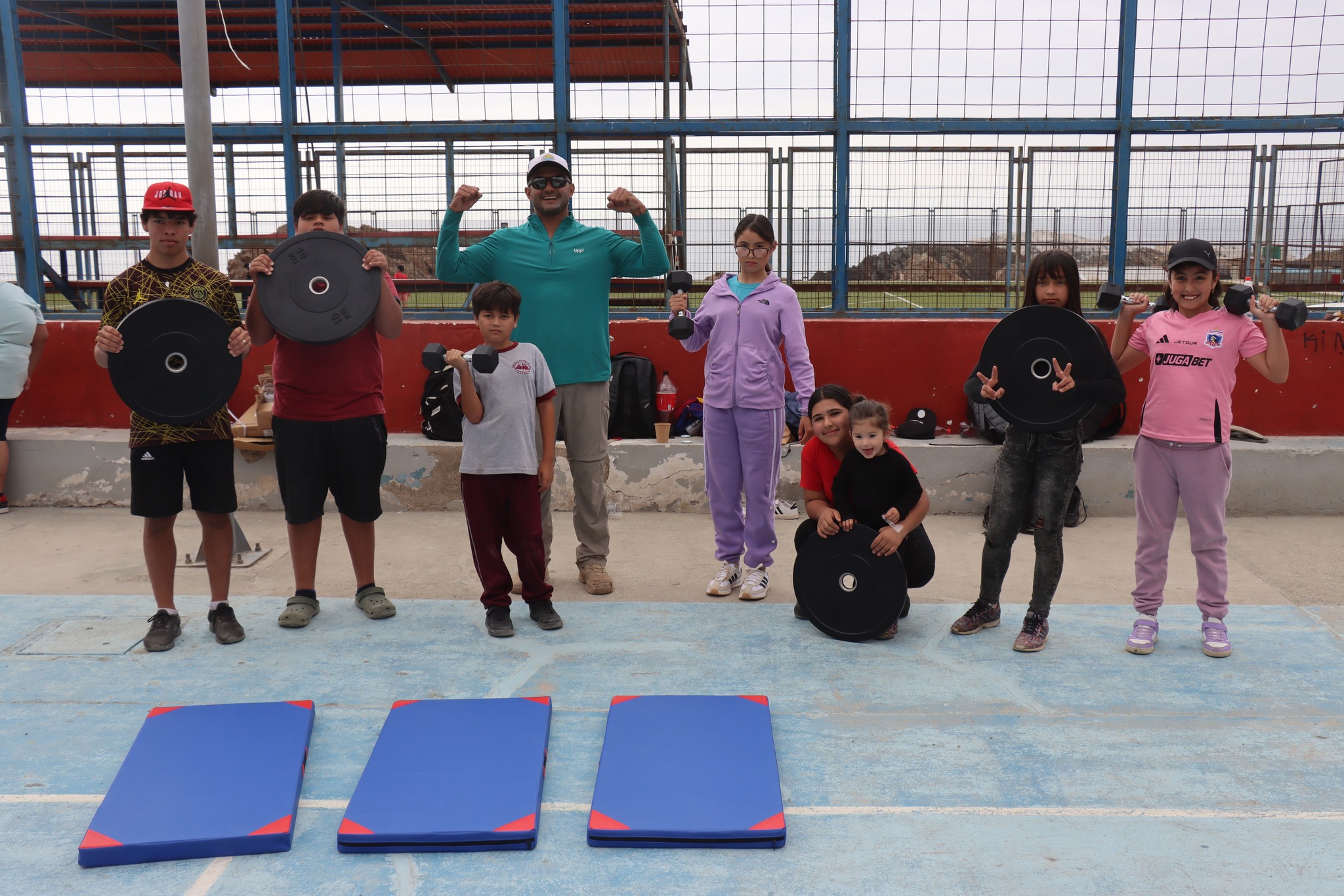 Grupo de niños y jóvenes mostrando equipamiento deportivo tras actividad física.