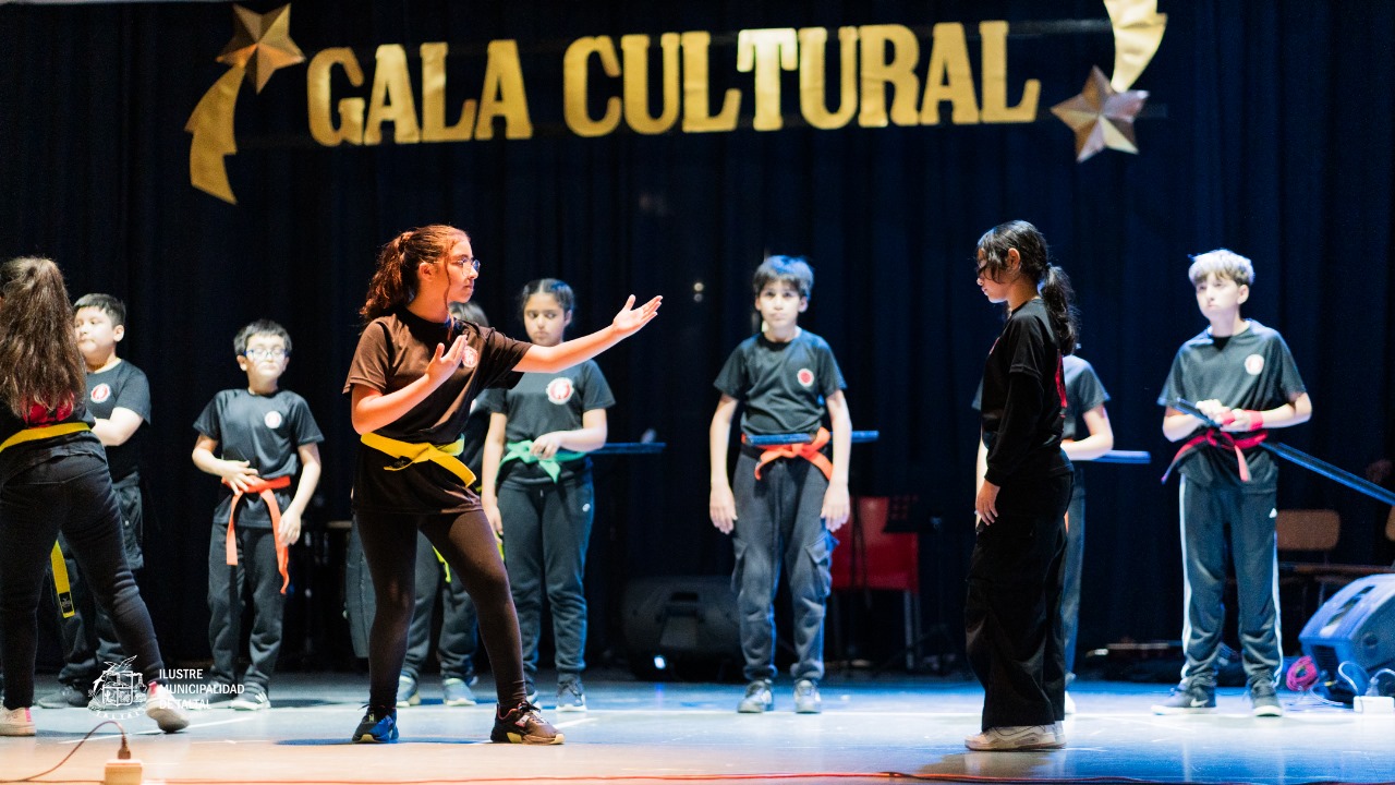 Alumna de la Academia de Artes Marciales con cinturón amarillo realizando una postura o kata frente a otra compañera.
