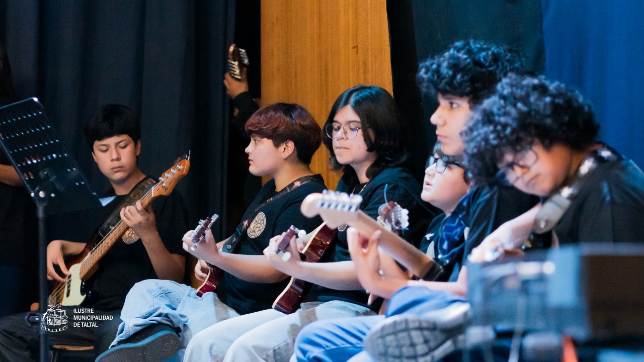 Primer plano lateral de jóvenes sentados tocando guitarras eléctricas y un bajo.