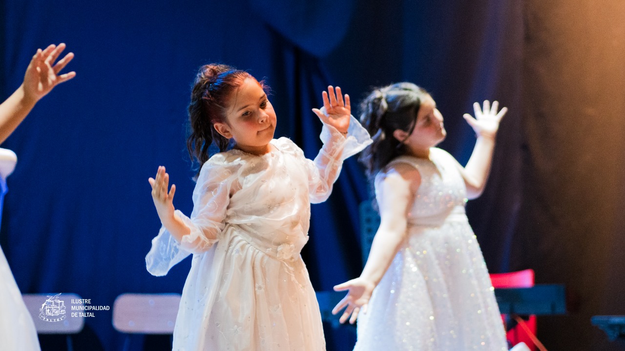 Primer plano de niñas del Taller de Danza en vestidos blancos, realizando movimientos con las manos levantadas.