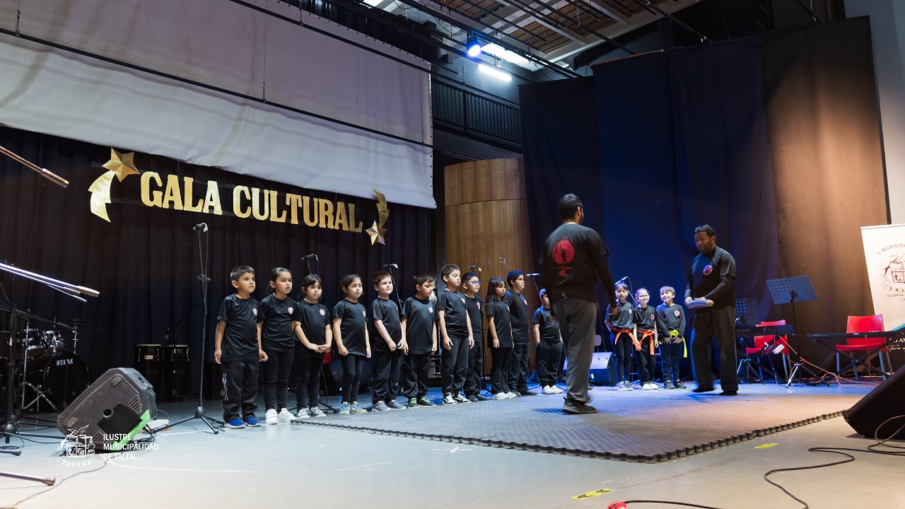 Grupo de niños pequeños de la Academia de Artes Marciales formados en el escenario con sus monitores.
