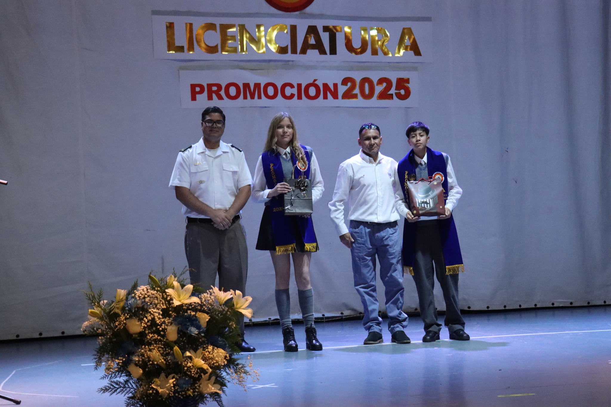 Estudiantes del Liceo Politécnico José Miguel Quiroz sobre el escenario durante la ceremonia de Licenciatura Promoción 2025.
