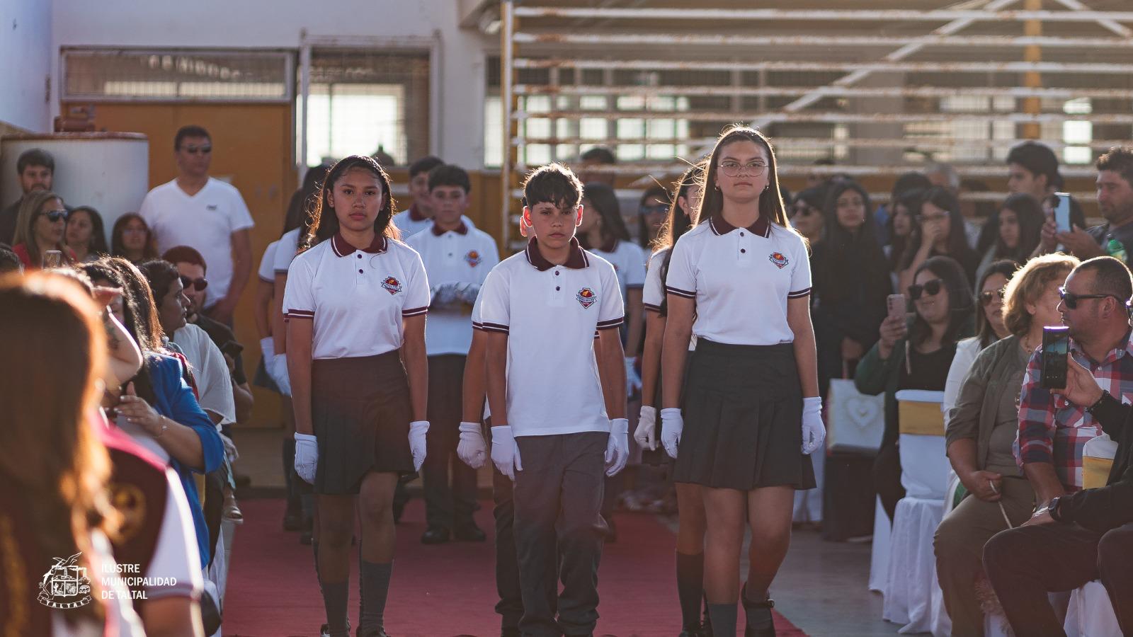 Alumnos desfilando con guantes blancos y uniforme de gala por la alfombra roja al inicio de la licenciatura.