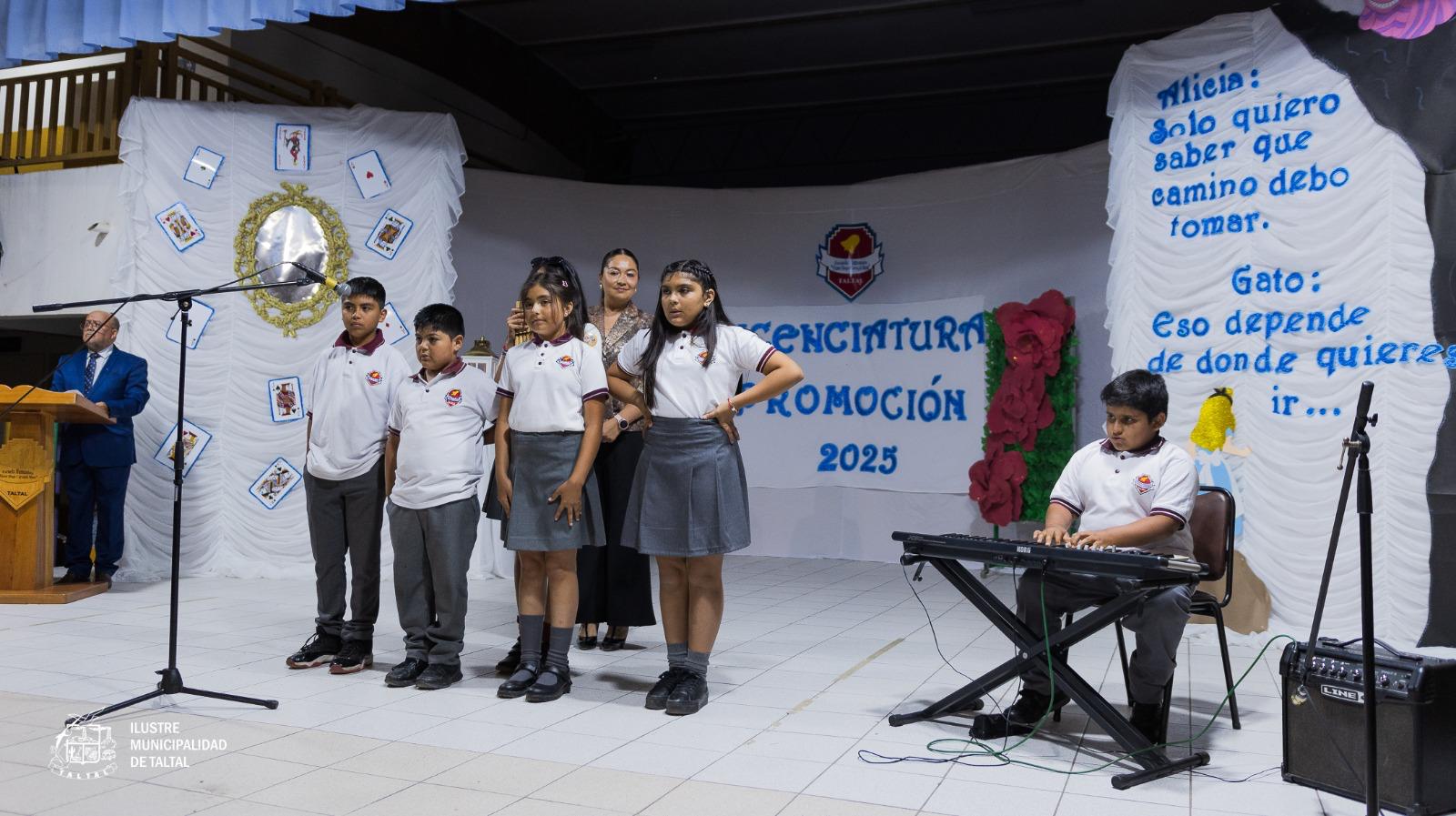 Estudiantes realizando una presentación musical con teclado en una ceremonia de licenciatura decorada con temática de Alicia en el País de las Maravillas.