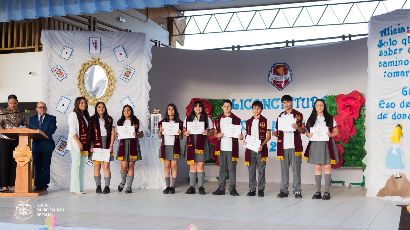 Estudiantes licenciados posando con sus diplomas de enseñanza básica junto a docente del establecimiento.