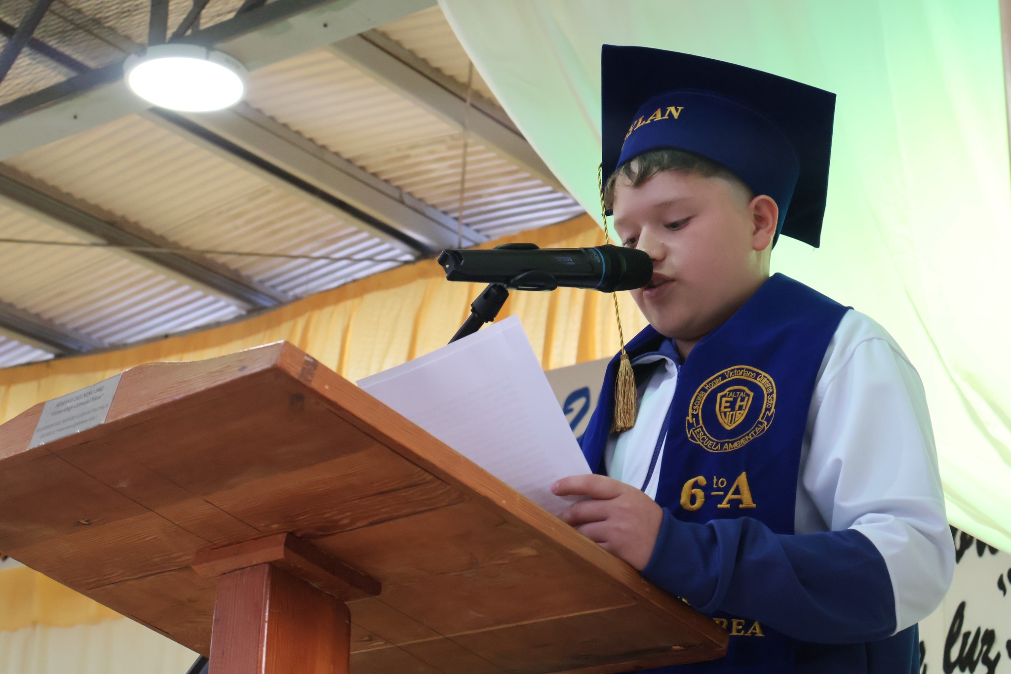 Estudiante de 6°A lee su discurso en el podio durante la ceremonia de despedida 2025 en la Escuela Hogar Victoriano Quinteros Soto de Taltal.
