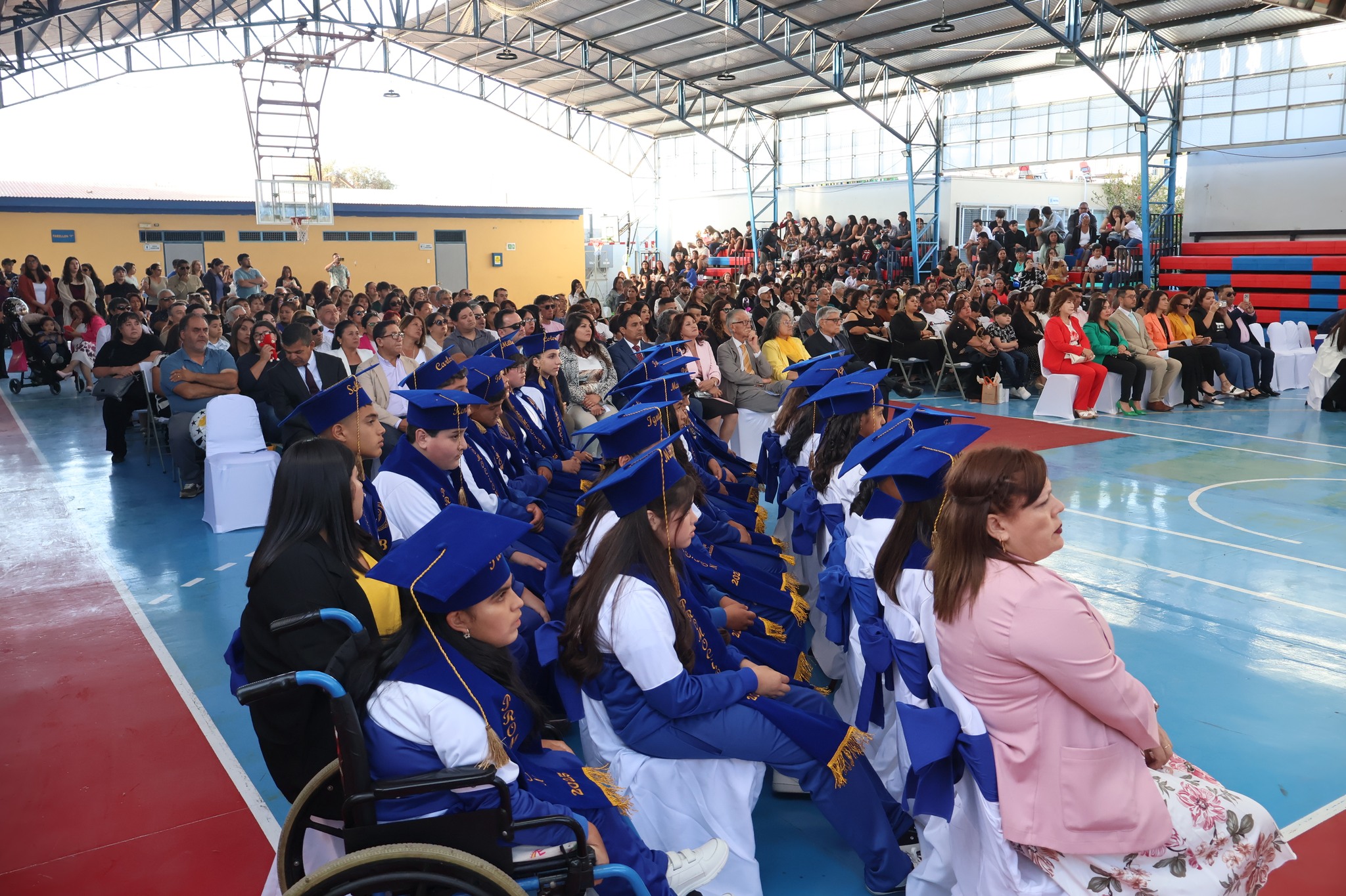 Vista general del gimnasio con estudiantes y familias durante la ceremonia 2025.