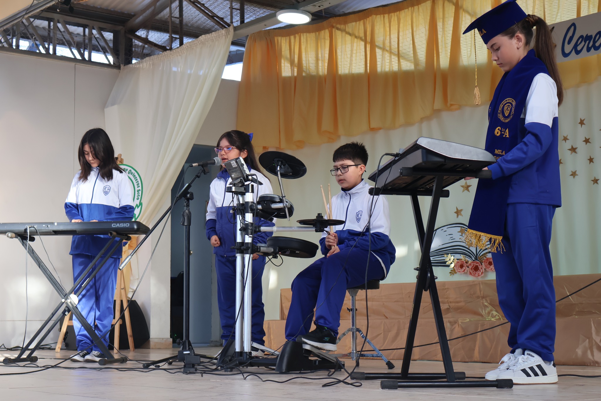 Presentación artística estudiantil con instrumentos en la ceremonia de sextos años.