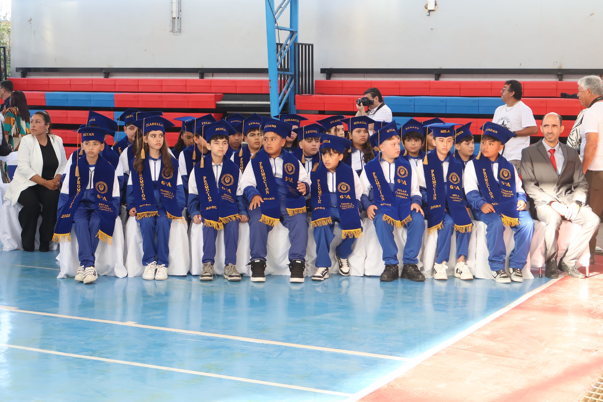 Estudiantes de sexto básico sentados con vestimenta de ceremonia y birretes 2025.