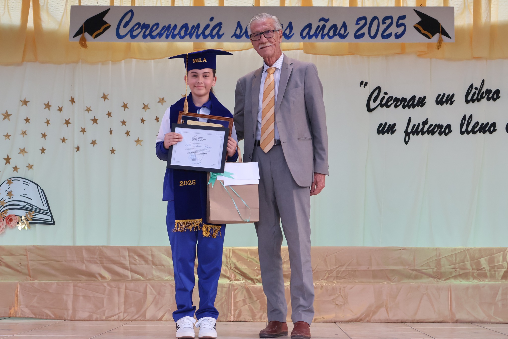 Estudiante recibe reconocimiento y posa con alcalde de Taltal Mario Acuña en el escenario 2025.