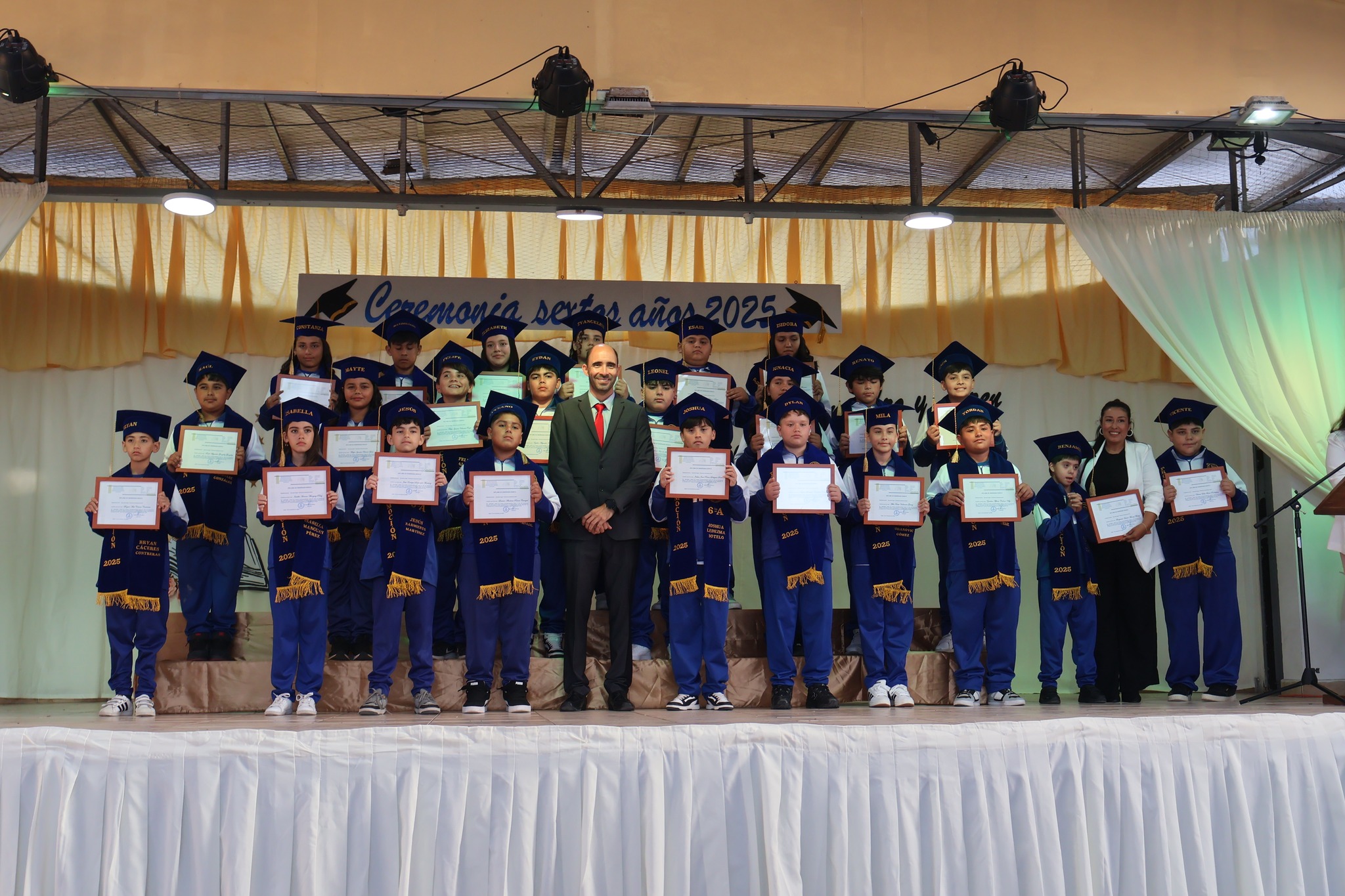 Foto final de estudiantes con distinciones y docente en el escenario de la ceremonia 2025.