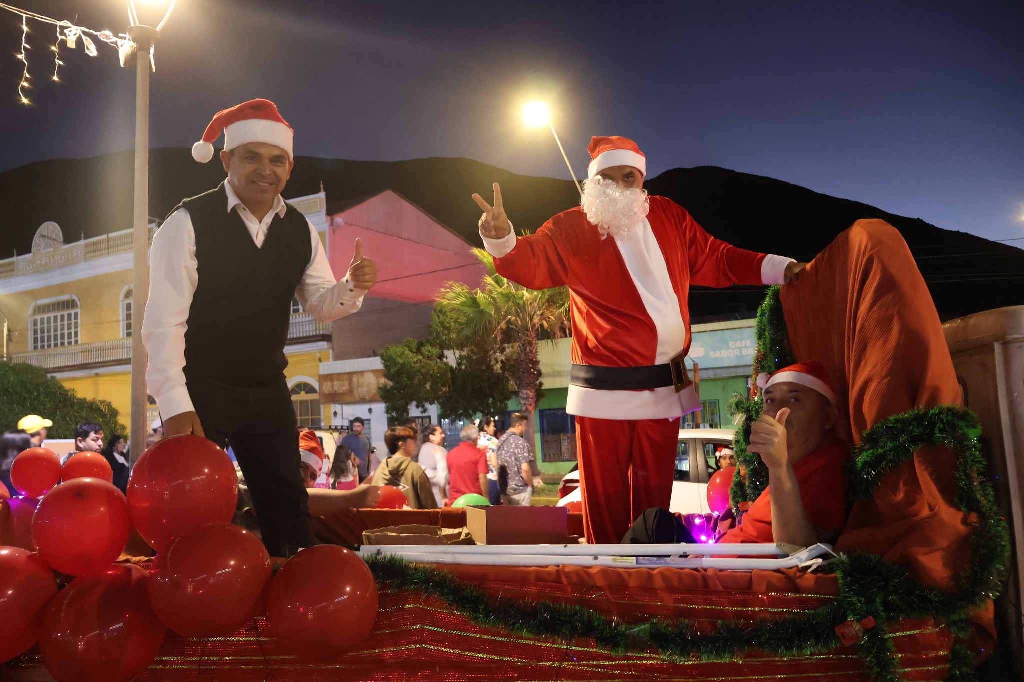 Papá Noel y equipo organizador sobre carro navideño, con globos y decoración, recorriendo las calles de Taltal.