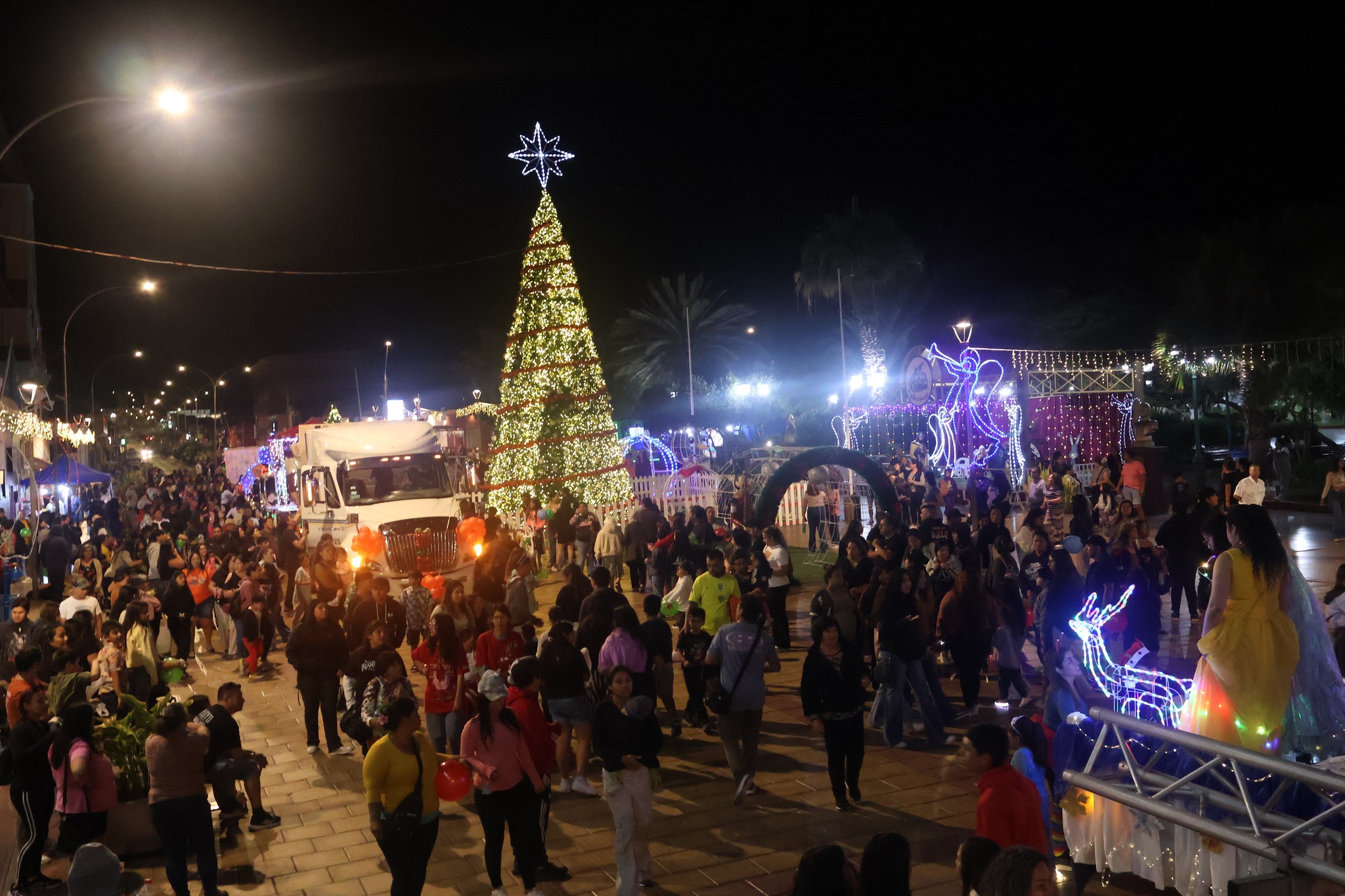 Vista general de la Plaza Prat con gran árbol navideño y alta asistencia de público durante la Caravana Navideña en Taltal.