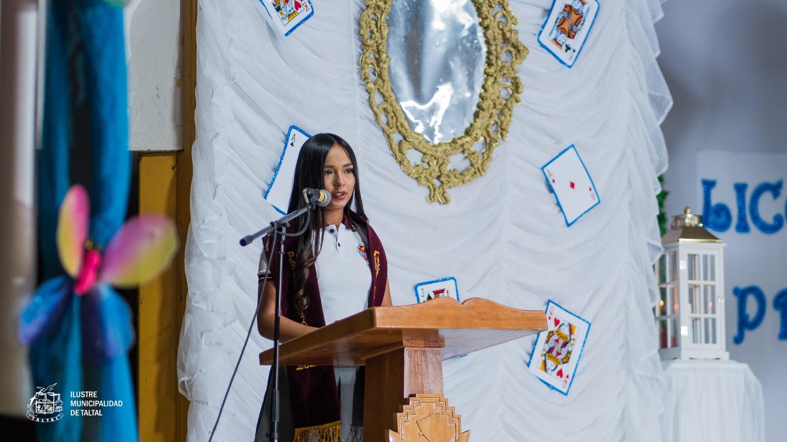 Una estudiante dando un discurso desde el podio durante la ceremonia de licenciatura de su promoción.