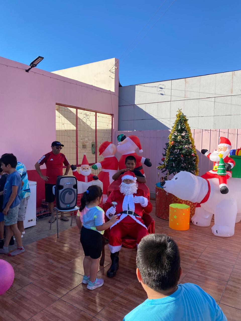 Vecinas y vecinos posan junto a Papá Noel en actividad navideña del barrio Eduardo Vigil en Taltal