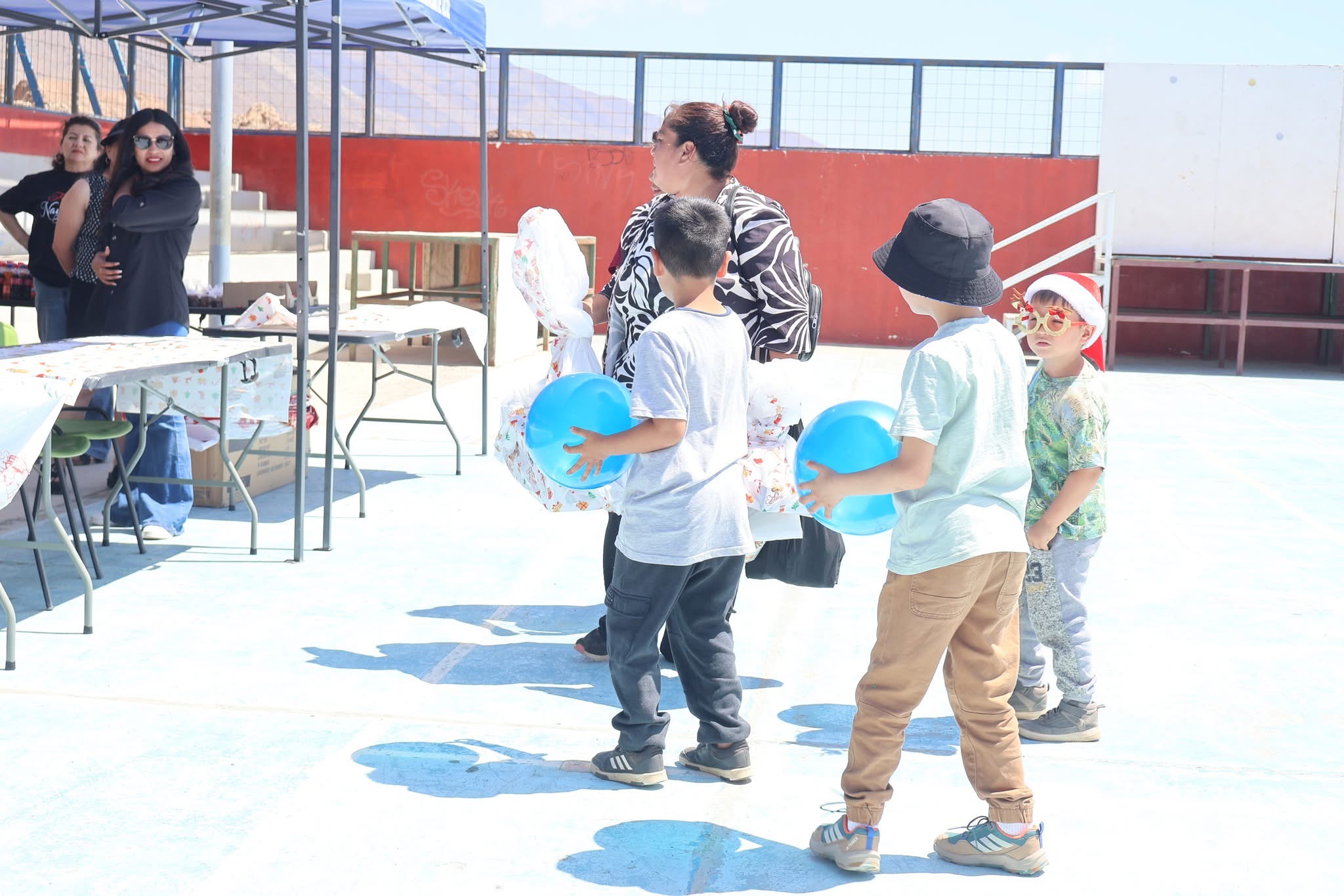Niños trasladan regalos y globos durante la jornada de Navidad organizada en Paposo.