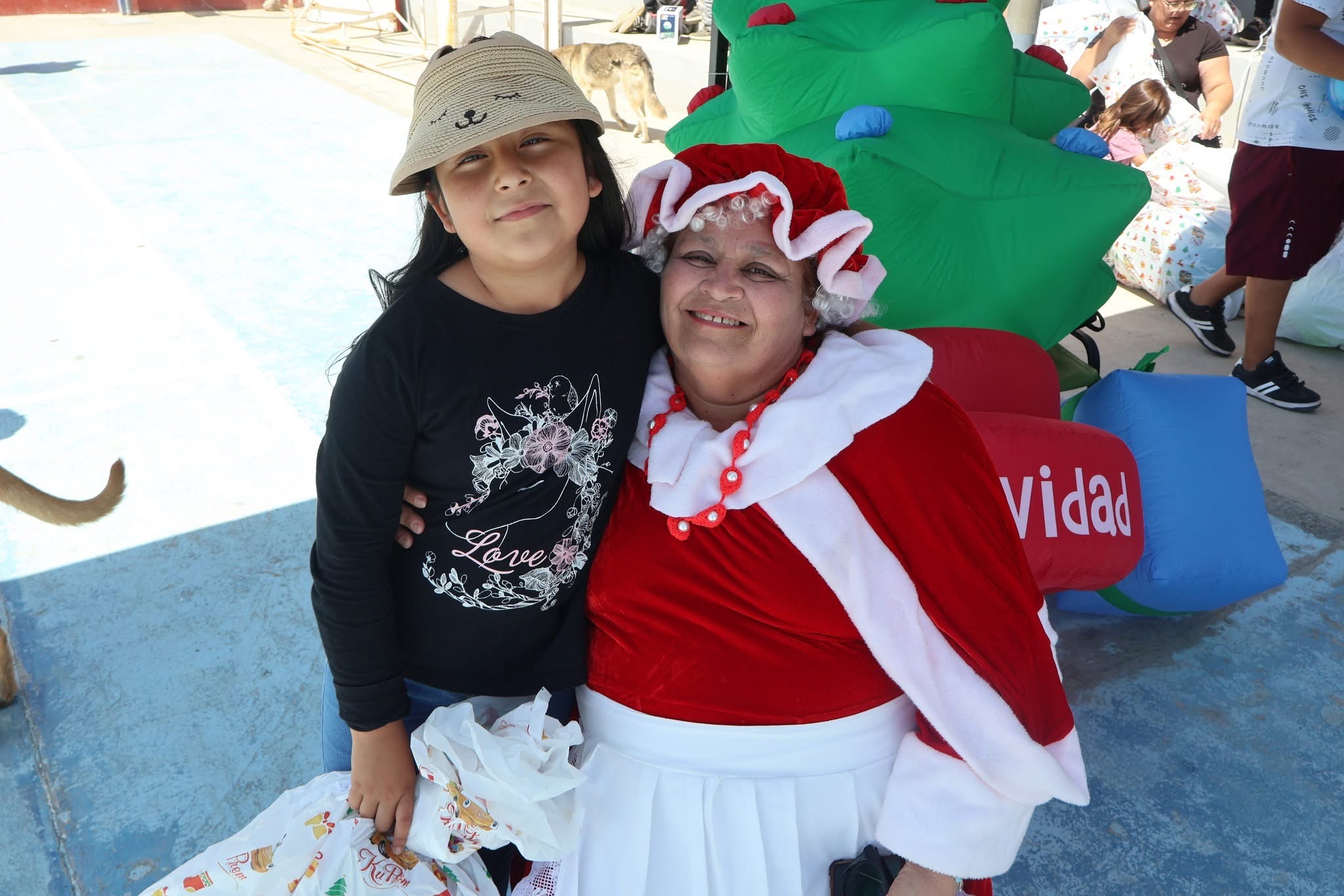 Niña posa junto a la Señora Closs en jornada de regalos de Navidad en Paposo.