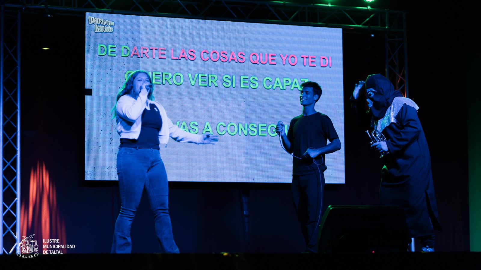 Vecinos cantando en dúo con apoyo de pantalla de letras en el evento masivo de Taltal.