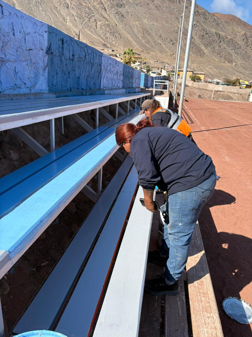 Personal municipal trabajando en la renovación estructural y estética de las zonas de espectadores.